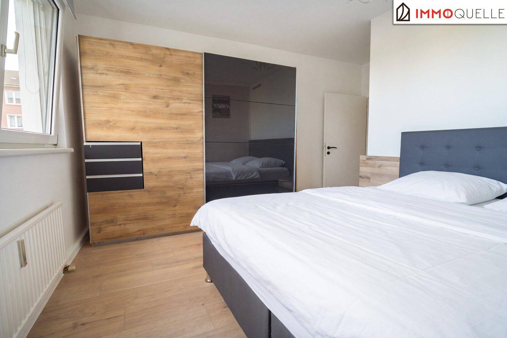 Schlafzimmer mit großem Kleiderschrank, Doppelbett und Laminatboden.