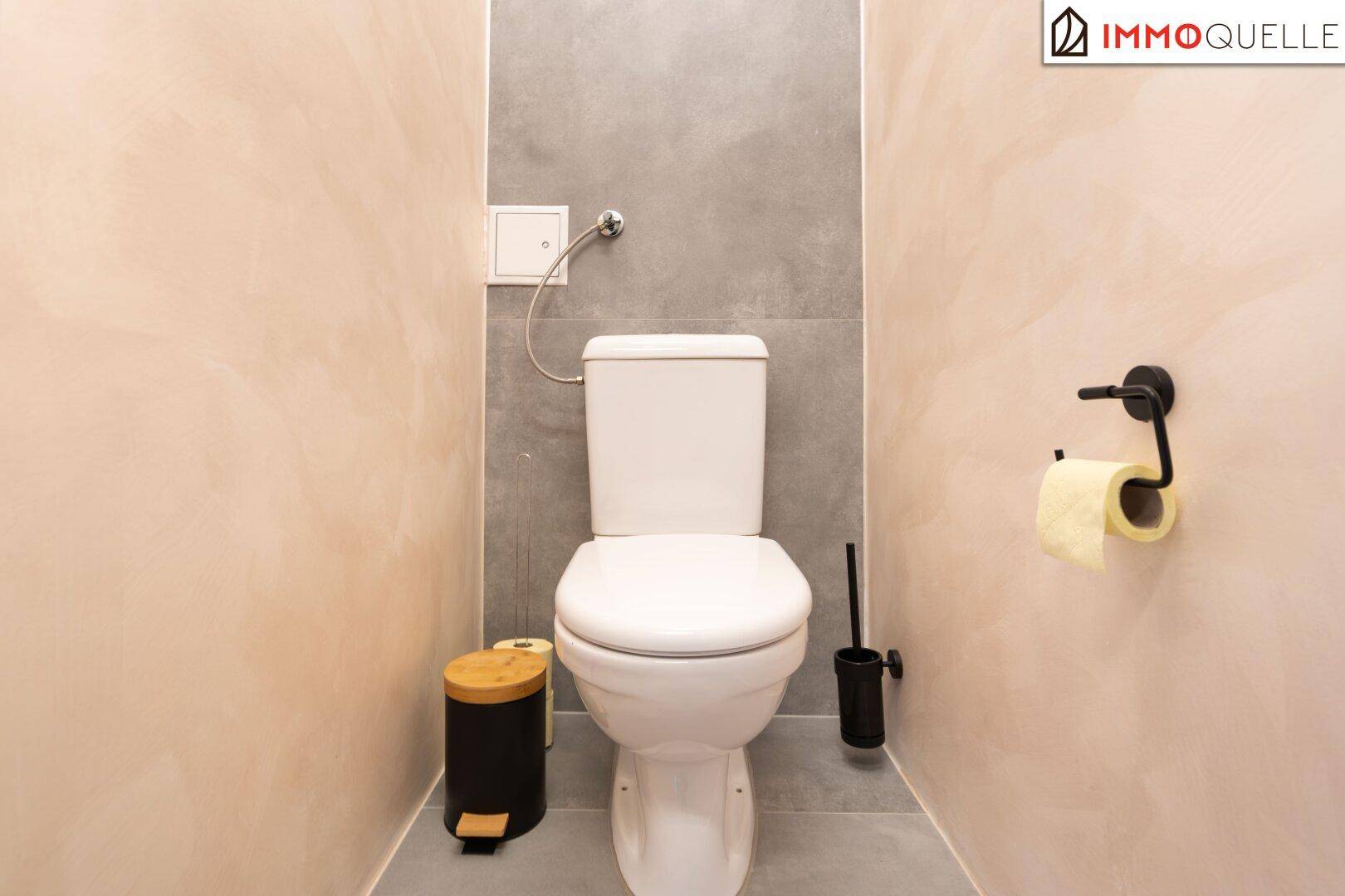 Separate Toilette mit Wand-WC und schlichten Fliesen an den Wänden.
