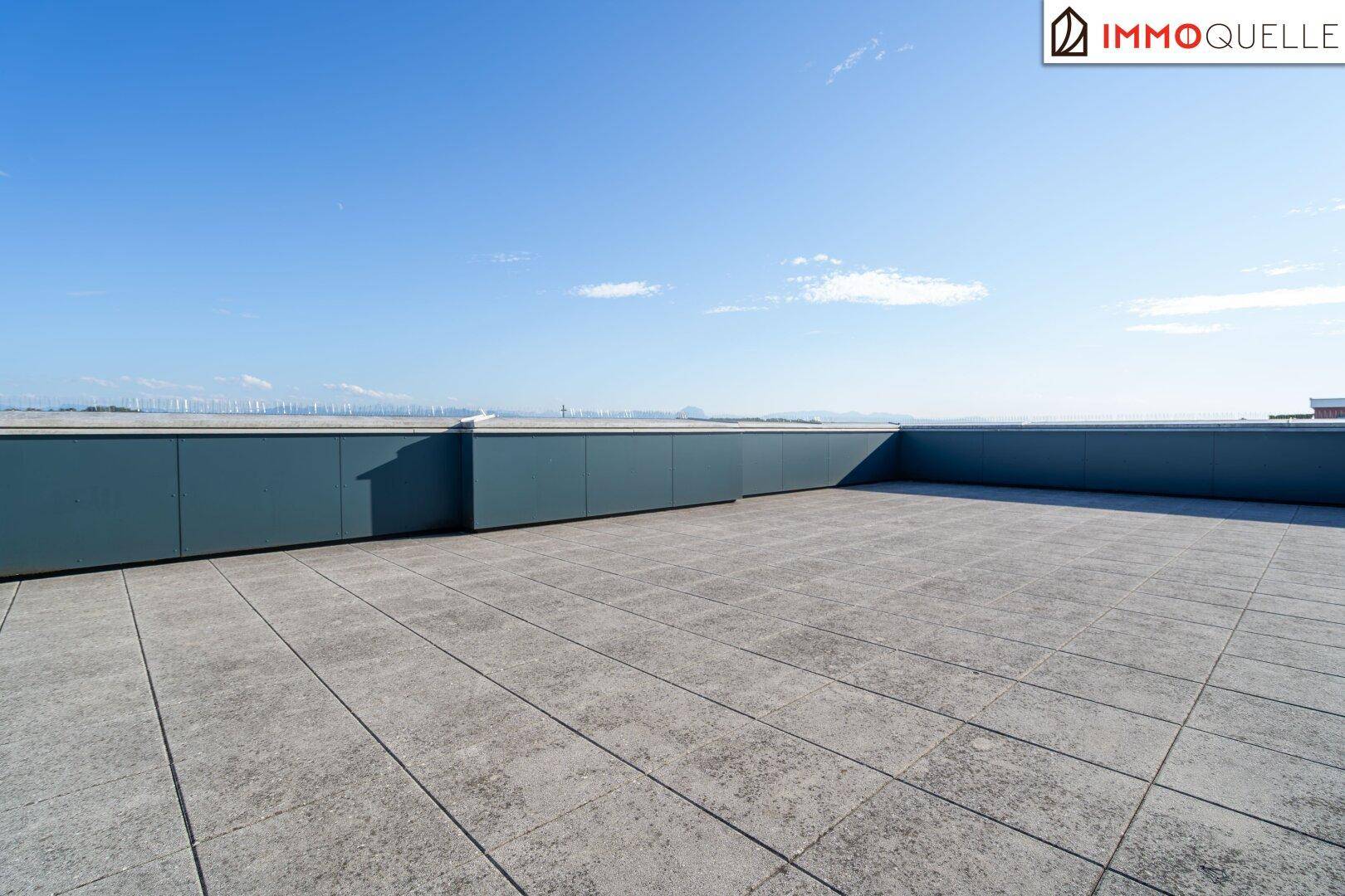 Weitläufige Dachterrasse mit Fliesenboden und Panoramablick auf die Umgebung.