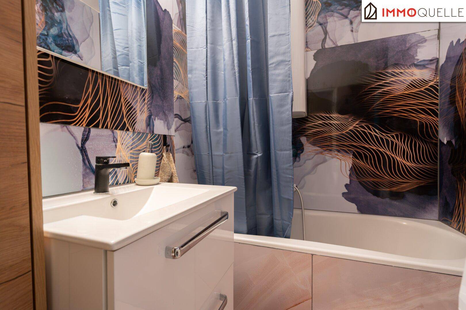 Badezimmer mit Badewanne, modernem Waschbecken und farbenfrohen Fliesen.