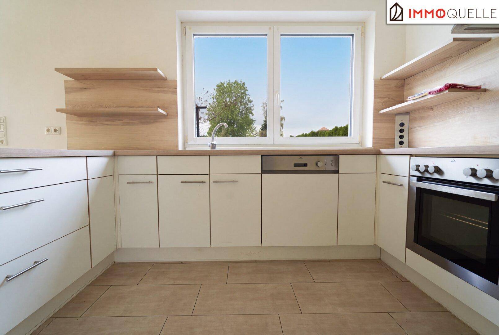 Funktionale Küche mit weißen Schränken, Holz-Arbeitsplatte, Spüle und Backofen.