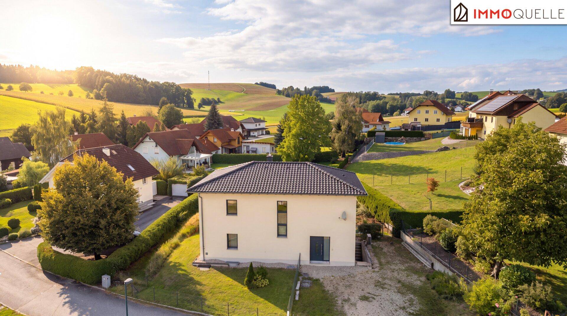 Vogelperspektive eines Einfamilienhauses in einer ländlichen Wohngegend mit viel Grün und Sonnenschein.