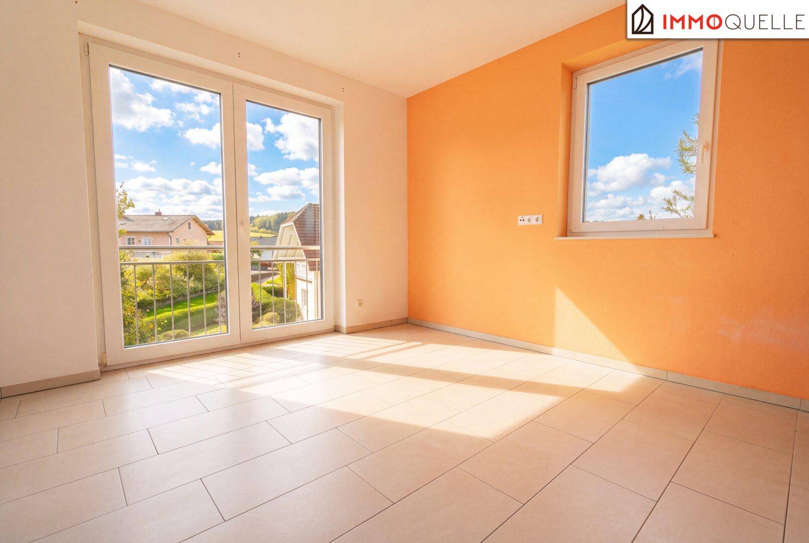 Helles, leeres Zimmer mit Fliesenboden, orangefarbener Wand und französischem Balkon.