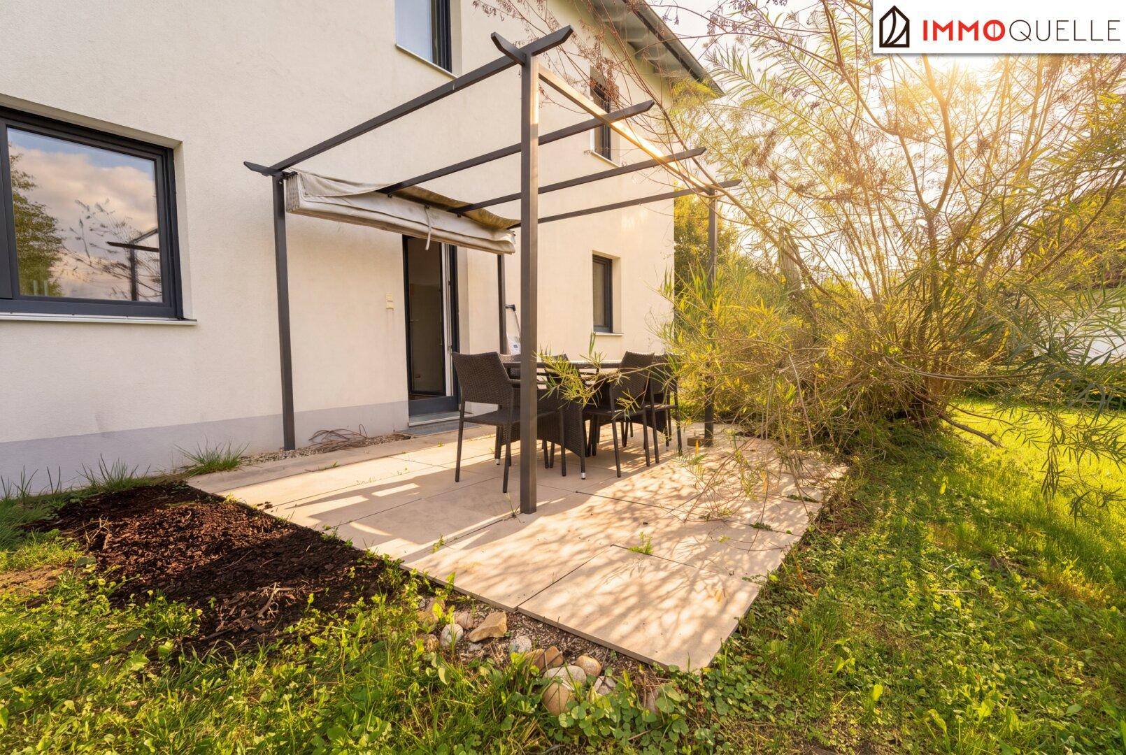 Sonniger Terrassenbereich mit Pergola und Gartenmöbeln, ideal für Mahlzeiten im Freien.
