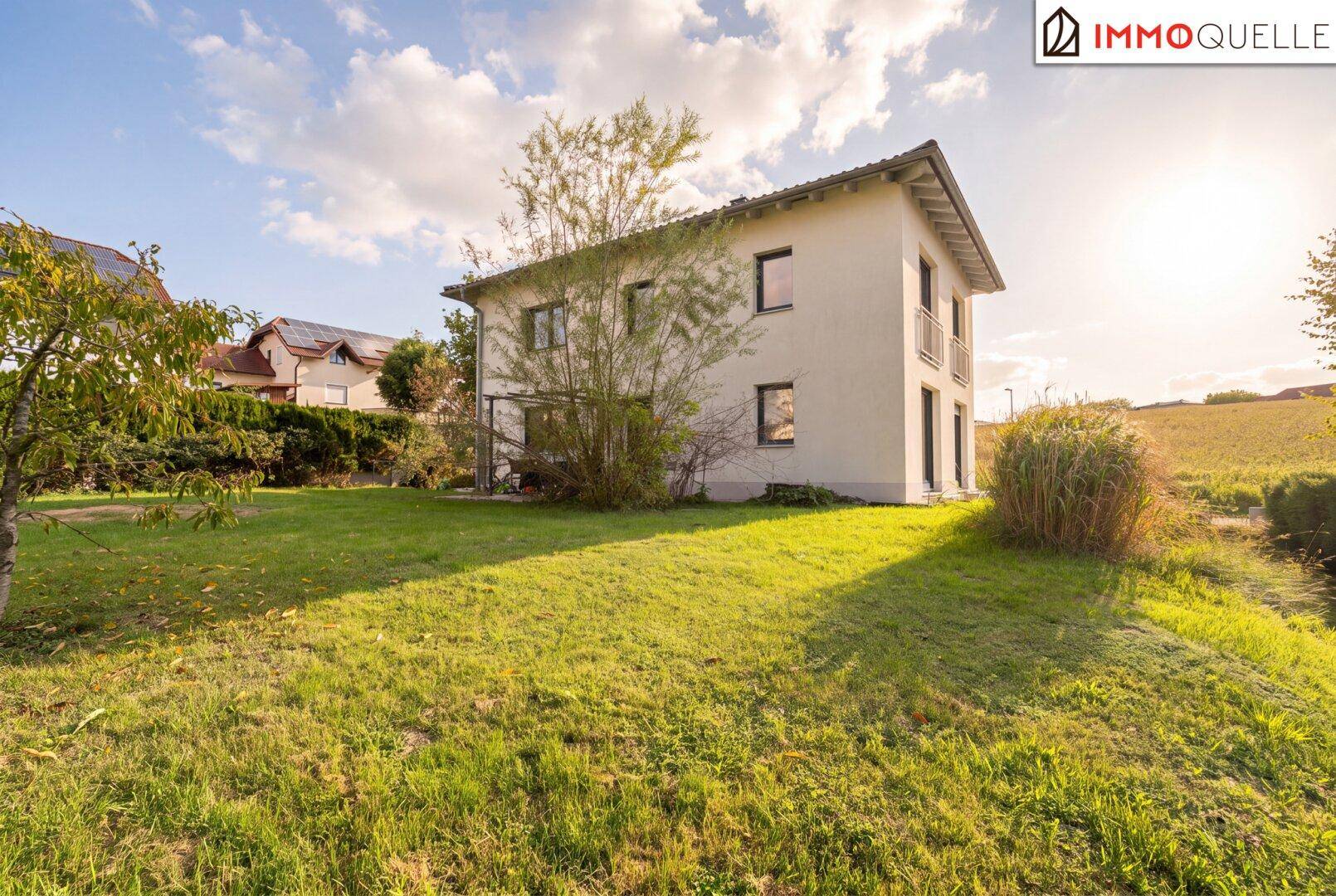 Seitenansicht des Hauses mit weitläufigem Garten und Blick auf die umliegende Landschaft.