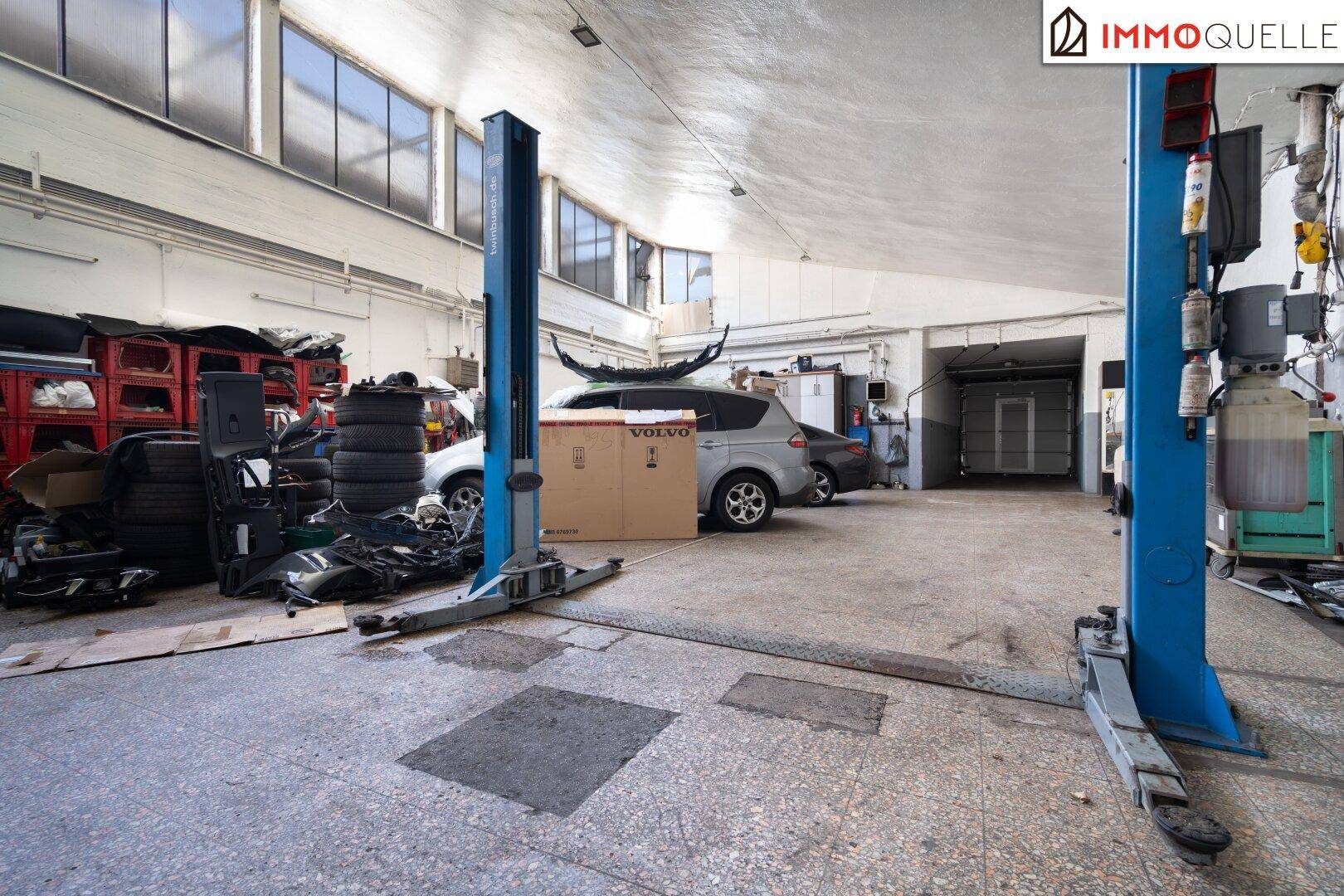 Geräumige Werkstatt mit Hebebühnen, Reifenstapeln und viel Platz für Fahrzeuge.