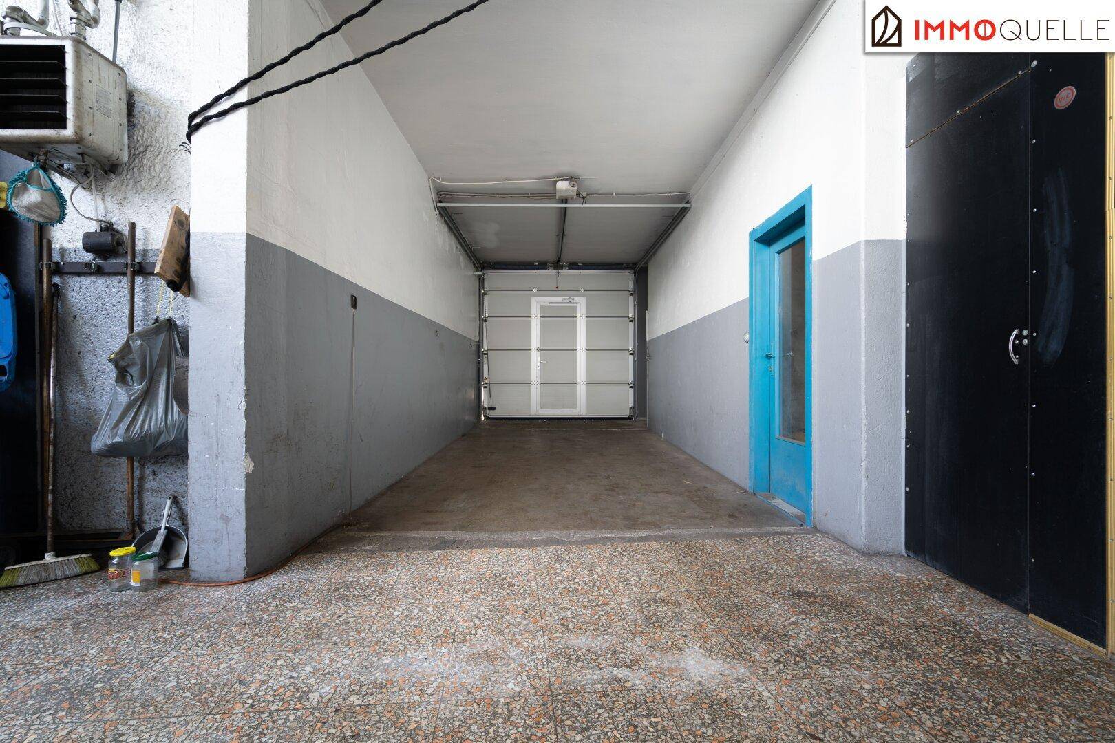Einfahrt zu einer Garage mit Rolltor und blauer Tür, funktional und gut zugänglich.