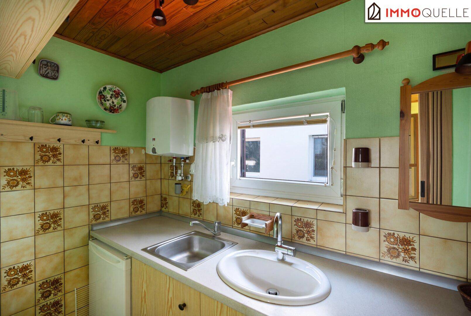 Funktionale Küche mit Spülbecken, Boiler und traditionellen Fliesen an den Wänden und auf dem Boden.