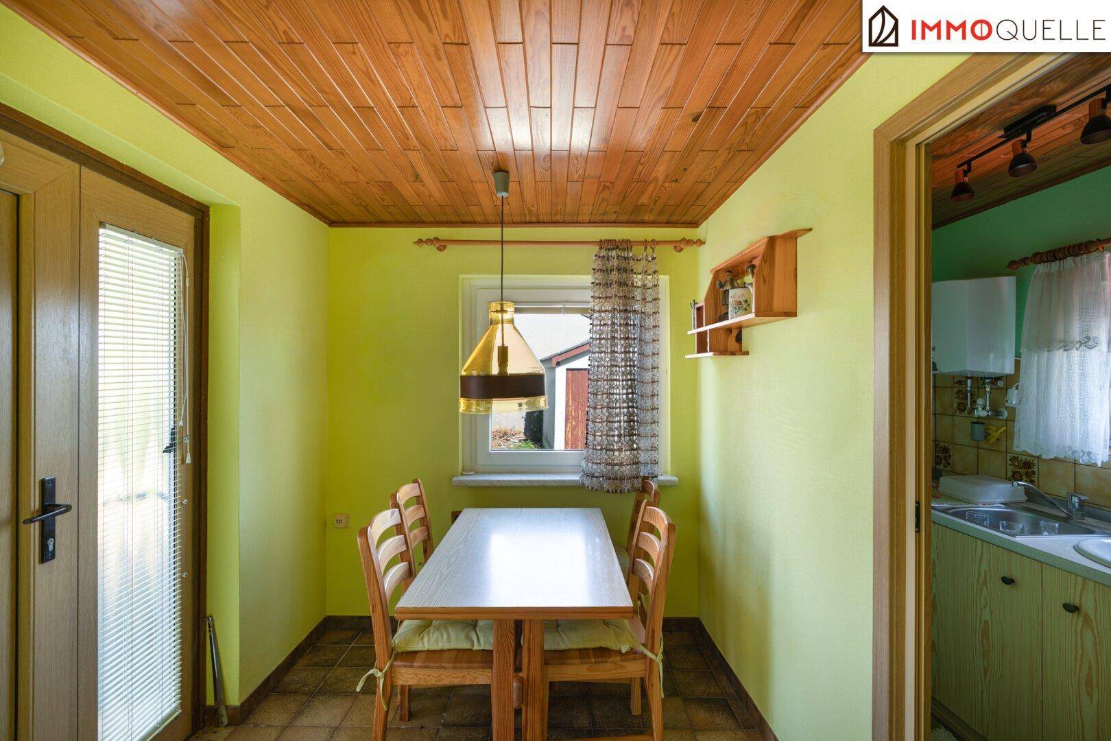 Heller Essbereich mit Holztisch, Holzdecke und traditioneller Einrichtung, angrenzend an die Küche.