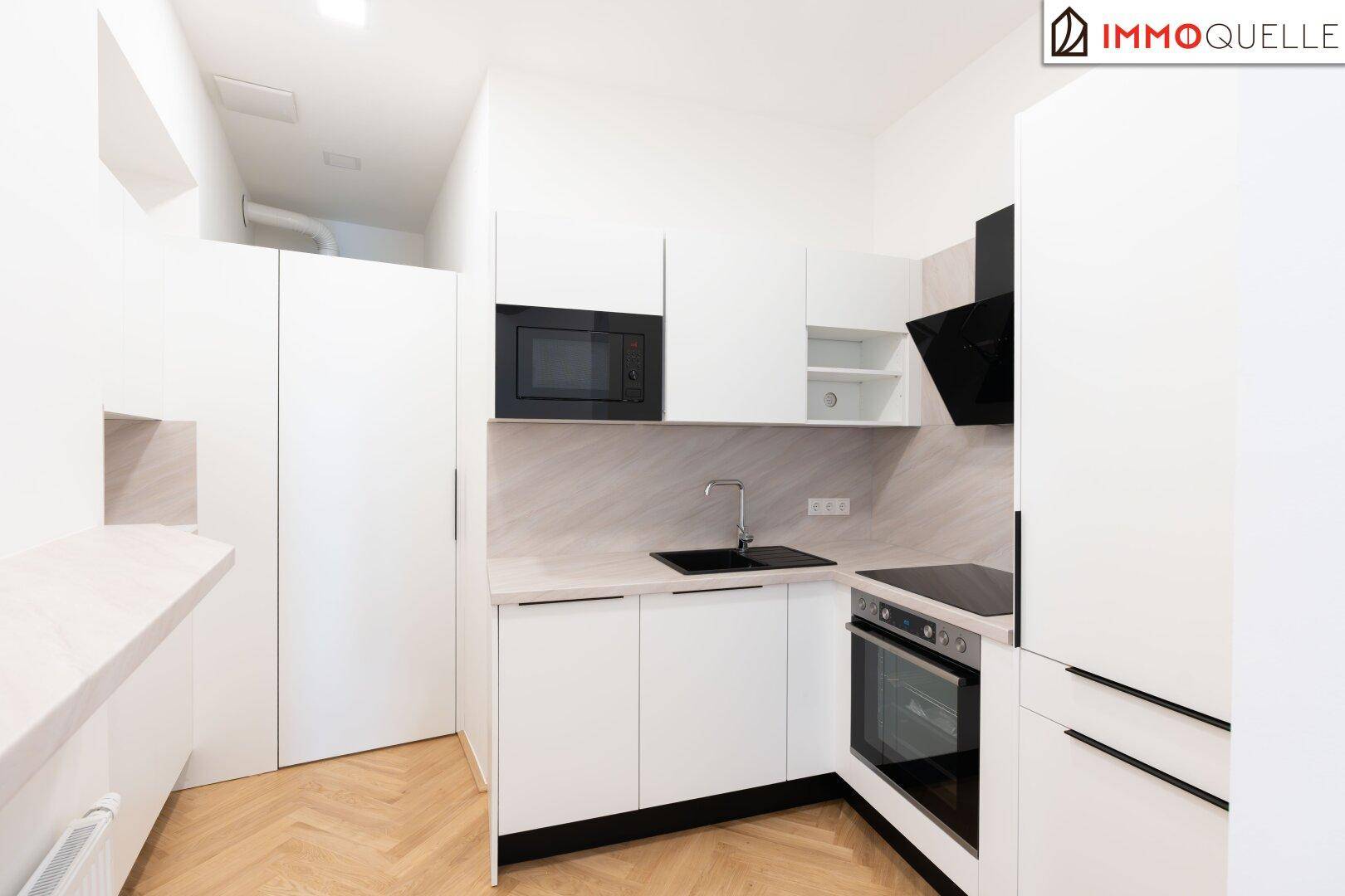 Moderne weiße Küche mit Einbaugeräten, schwarzer Spüle und Dunstabzugshaube, neuwertig.