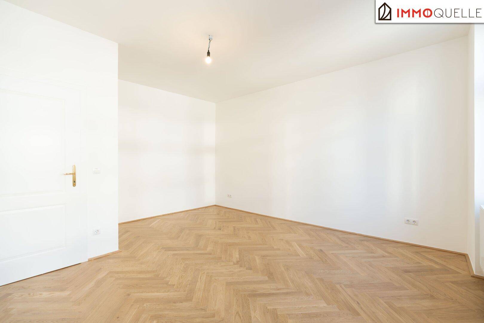 Helles, leeres Schlafzimmer mit Fischgrätparkett und weißer Tür, ideal für individuelle Gestaltung.