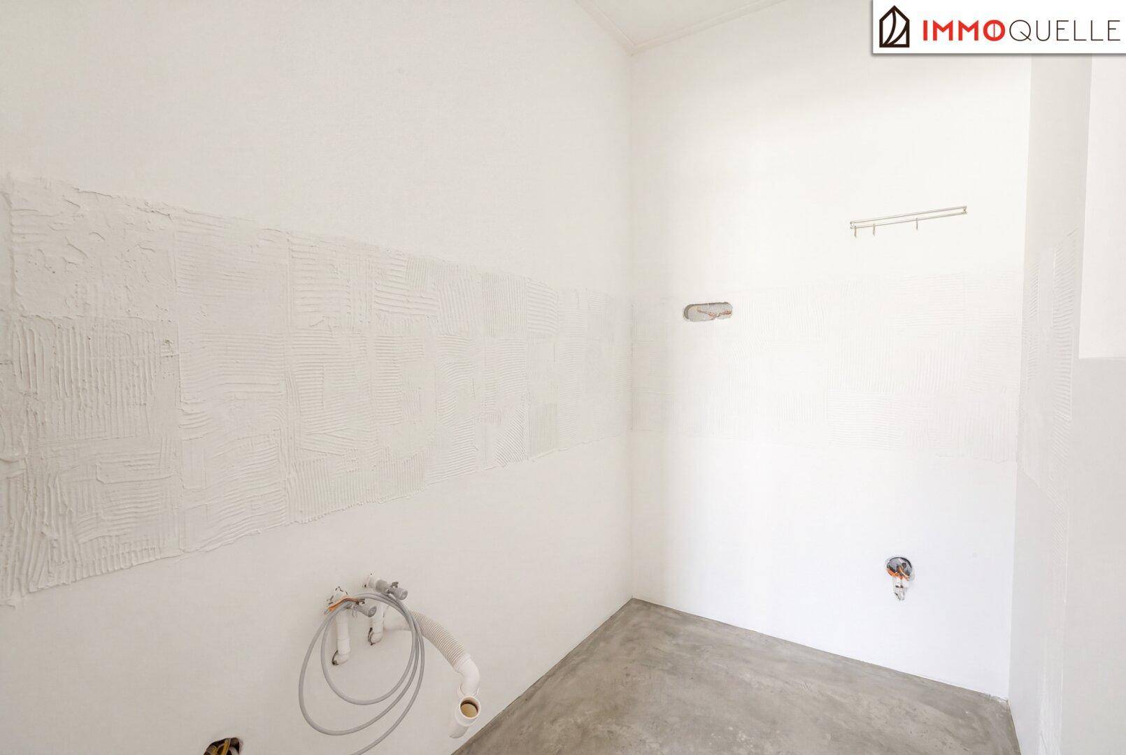 Unfertiger Raum mit Anschlüssen für Sanitärinstallationen und vorbereiteten Wänden.