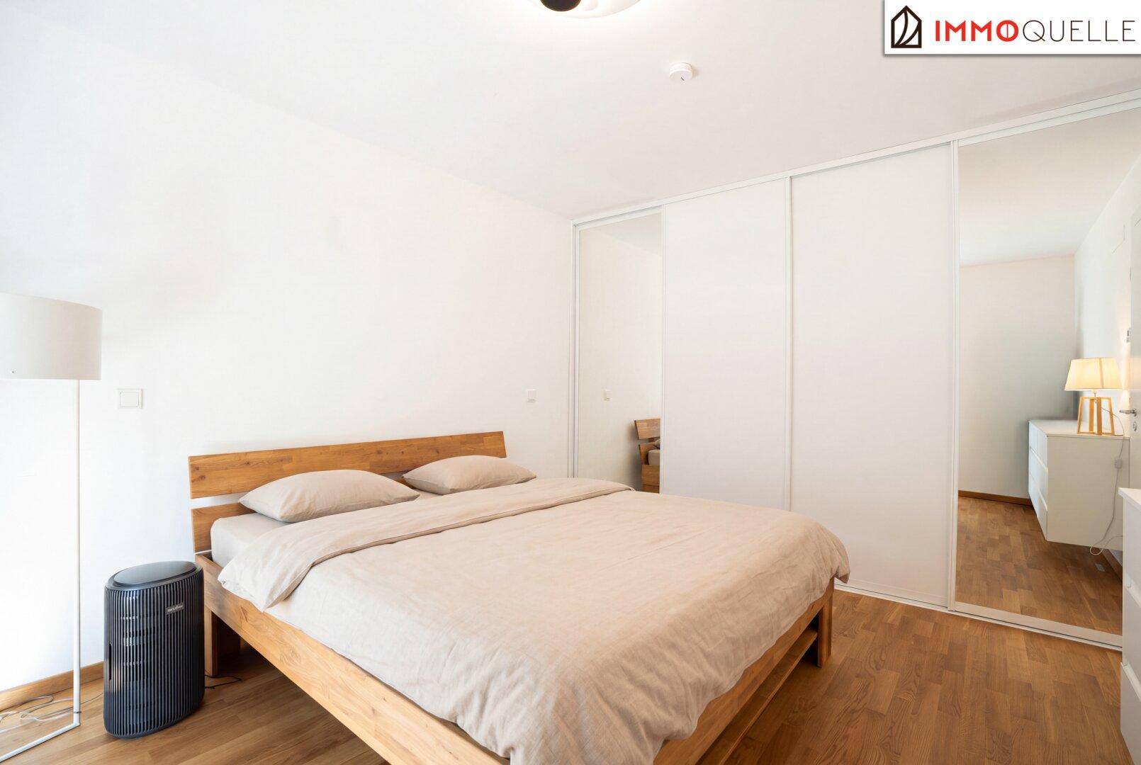 Gemütliches Schlafzimmer mit Holzbett, Parkettboden und integriertem Spiegelschrank.