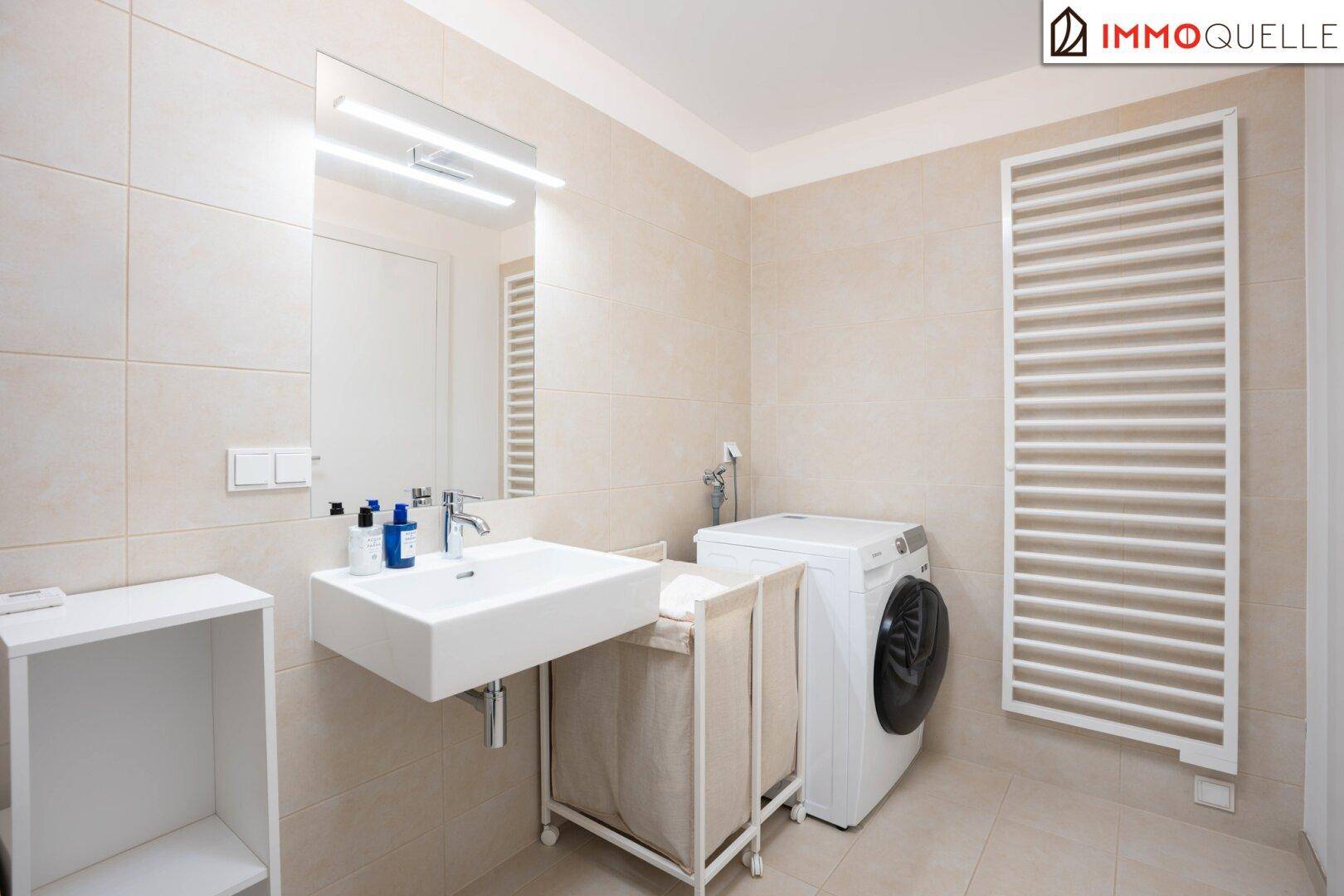 Modernes Badezimmer mit Waschbecken, Waschmaschine und beheiztem Handtuchhalter.