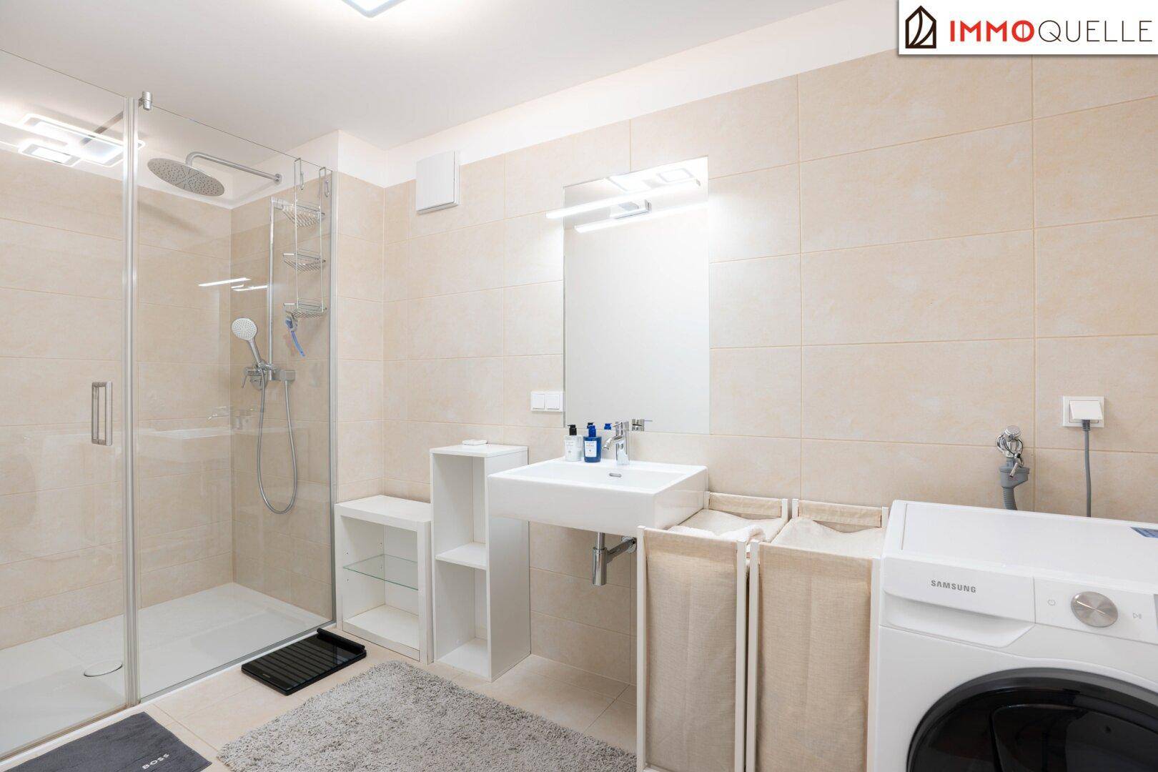 Helles Badezimmer mit begehbarer Dusche, Waschbecken und Waschmaschine.