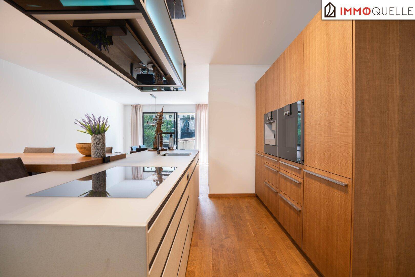 Hochwertige Einbauküche mit Holzfronten, Kochinsel und modernen Geräten in offenem Design.