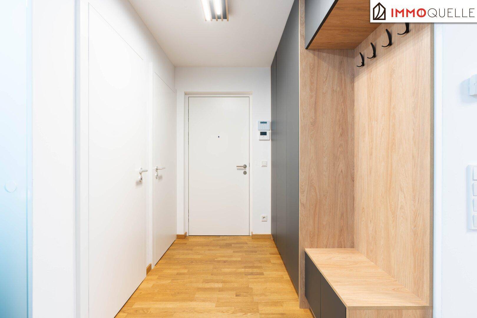 Moderner Eingangsbereich mit Holzboden, Garderobe und weißen Türen.