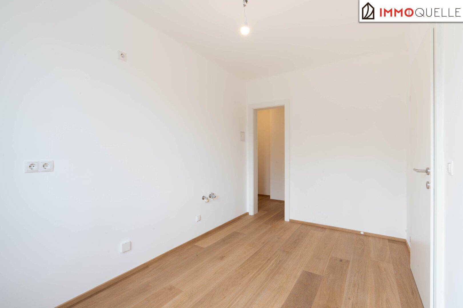 Leerer Raum mit hellem Parkettboden und Türzugang, ideal für individuelle Gestaltung.
