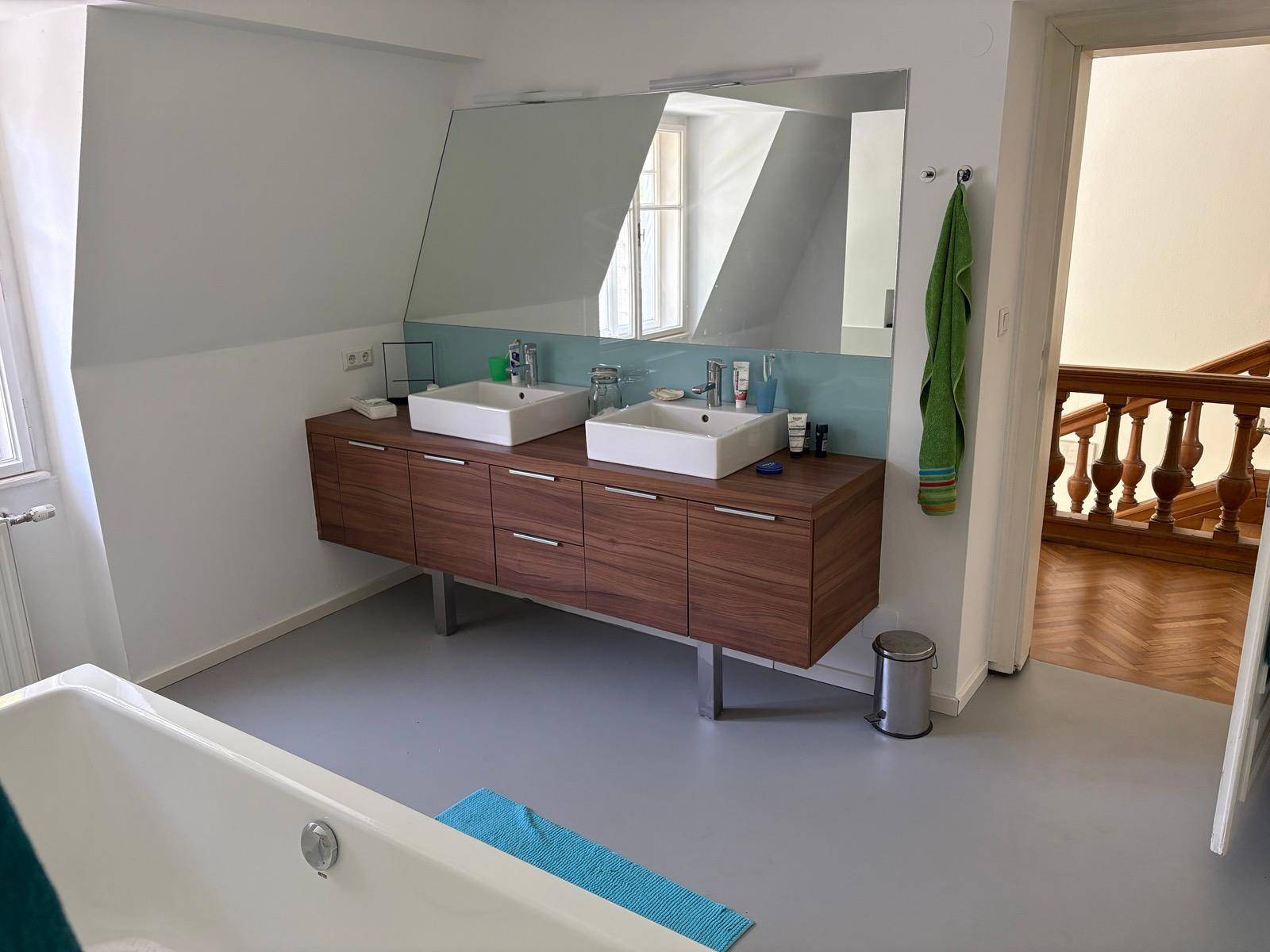 Modernes Badezimmer mit Doppelwaschbecken, großer Spiegelfläche und Badewanne.