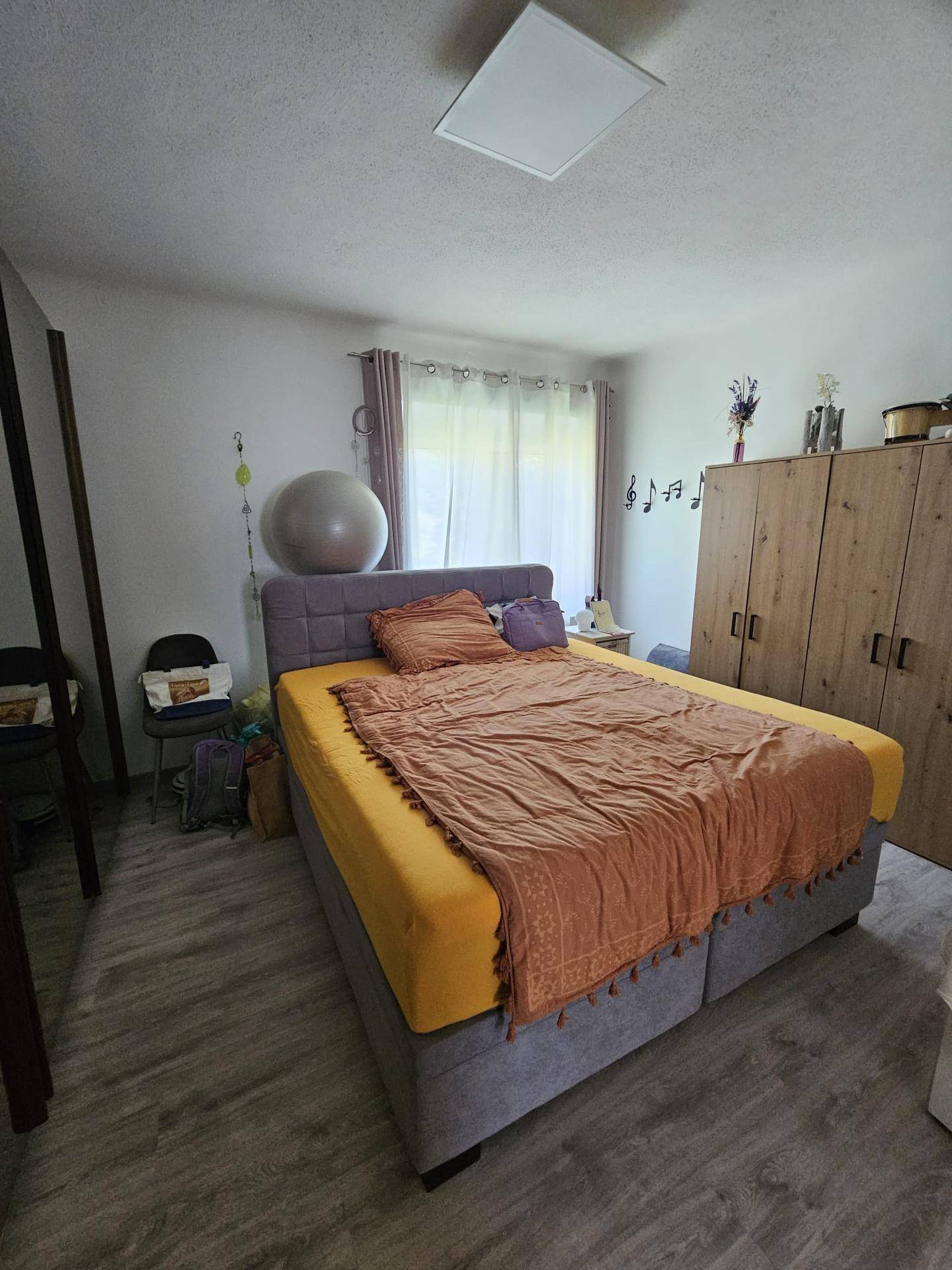 Schlafzimmer mit Doppelbett, Laminatboden und großem Fenster für viel Tageslicht.