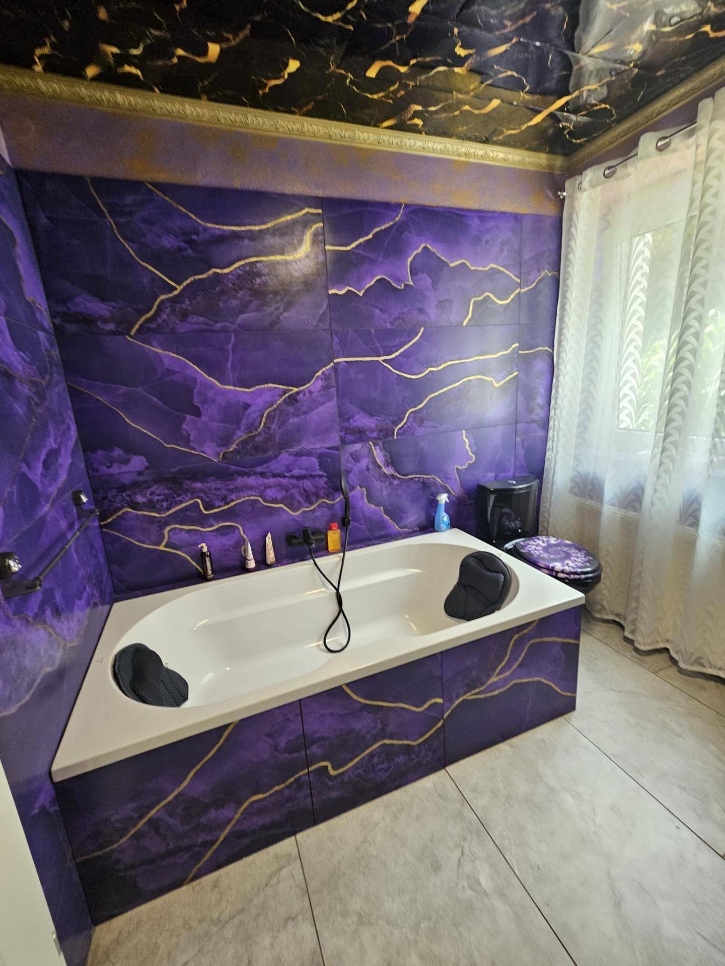 Badezimmer mit lila Marmorfliesen, Badewanne und Fenster für Tageslicht.
