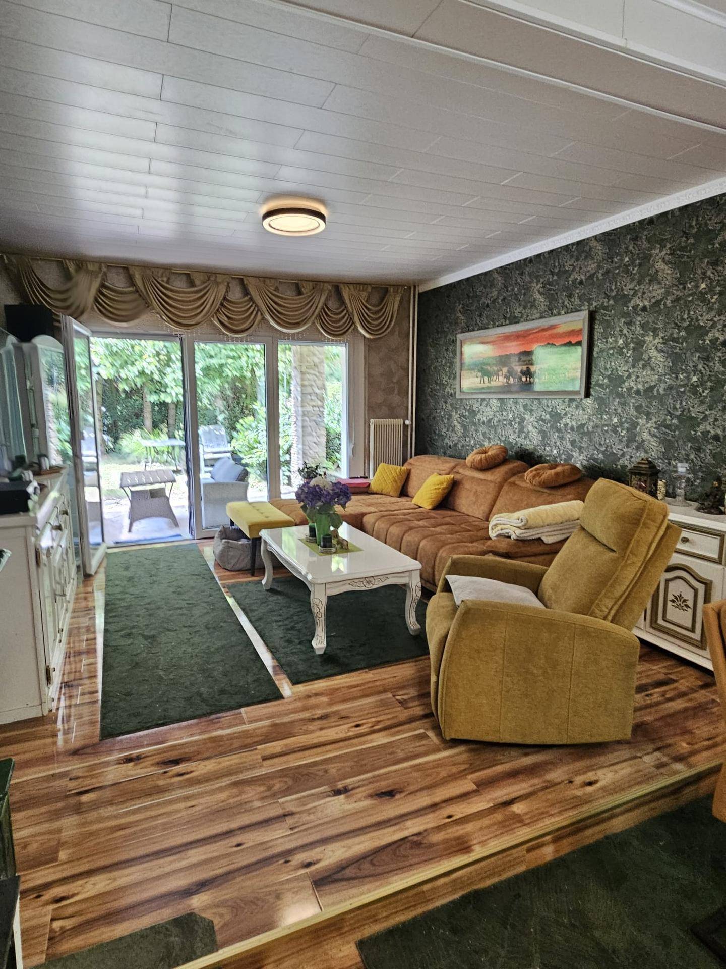 Gemütliches Wohnzimmer mit bequemer Couch, Holzboden und Zugang zur Terrasse.