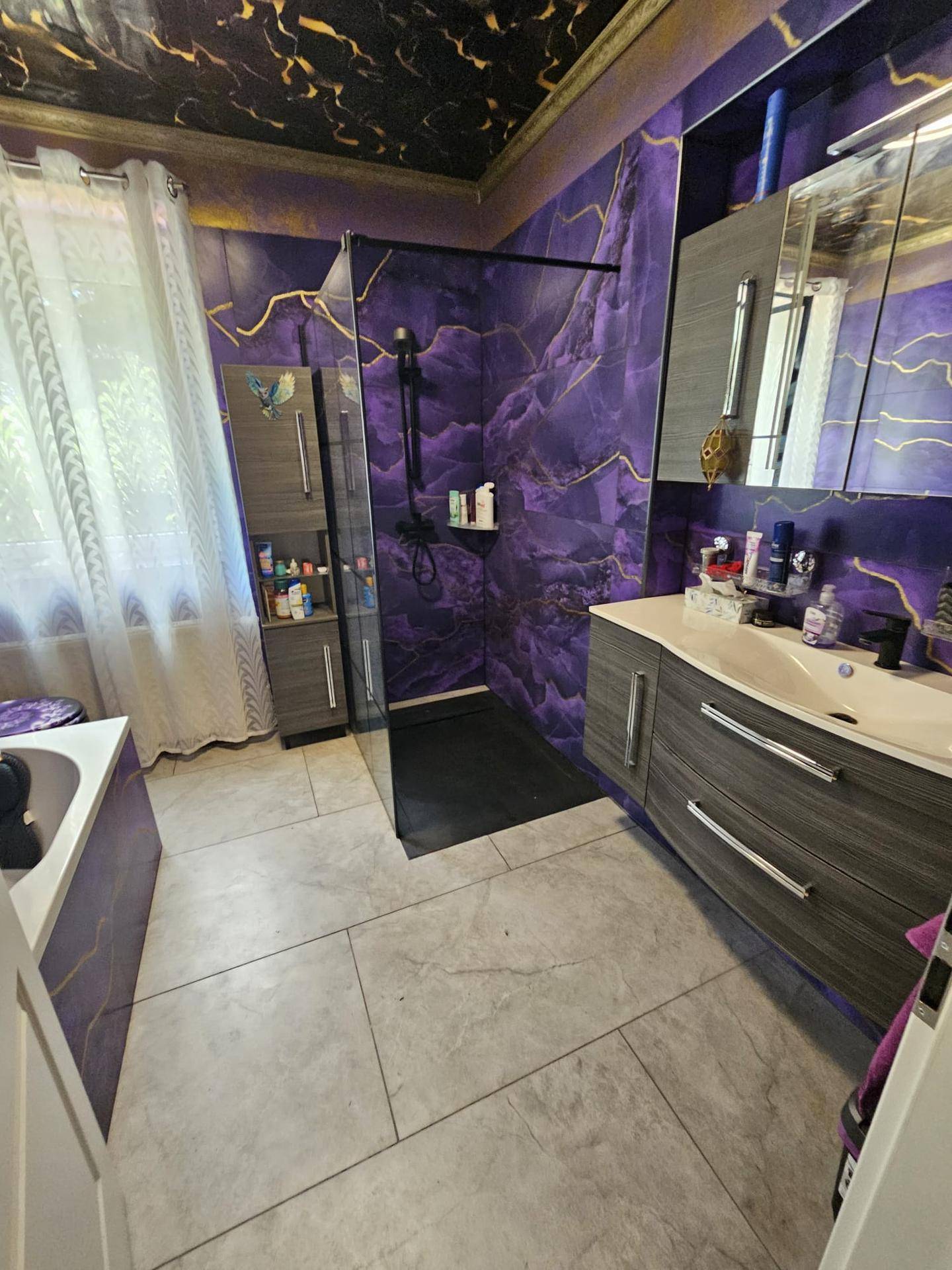 Modernes Badezimmer mit lila Marmorfliesen, Dusche und Waschtisch mit Spiegel.