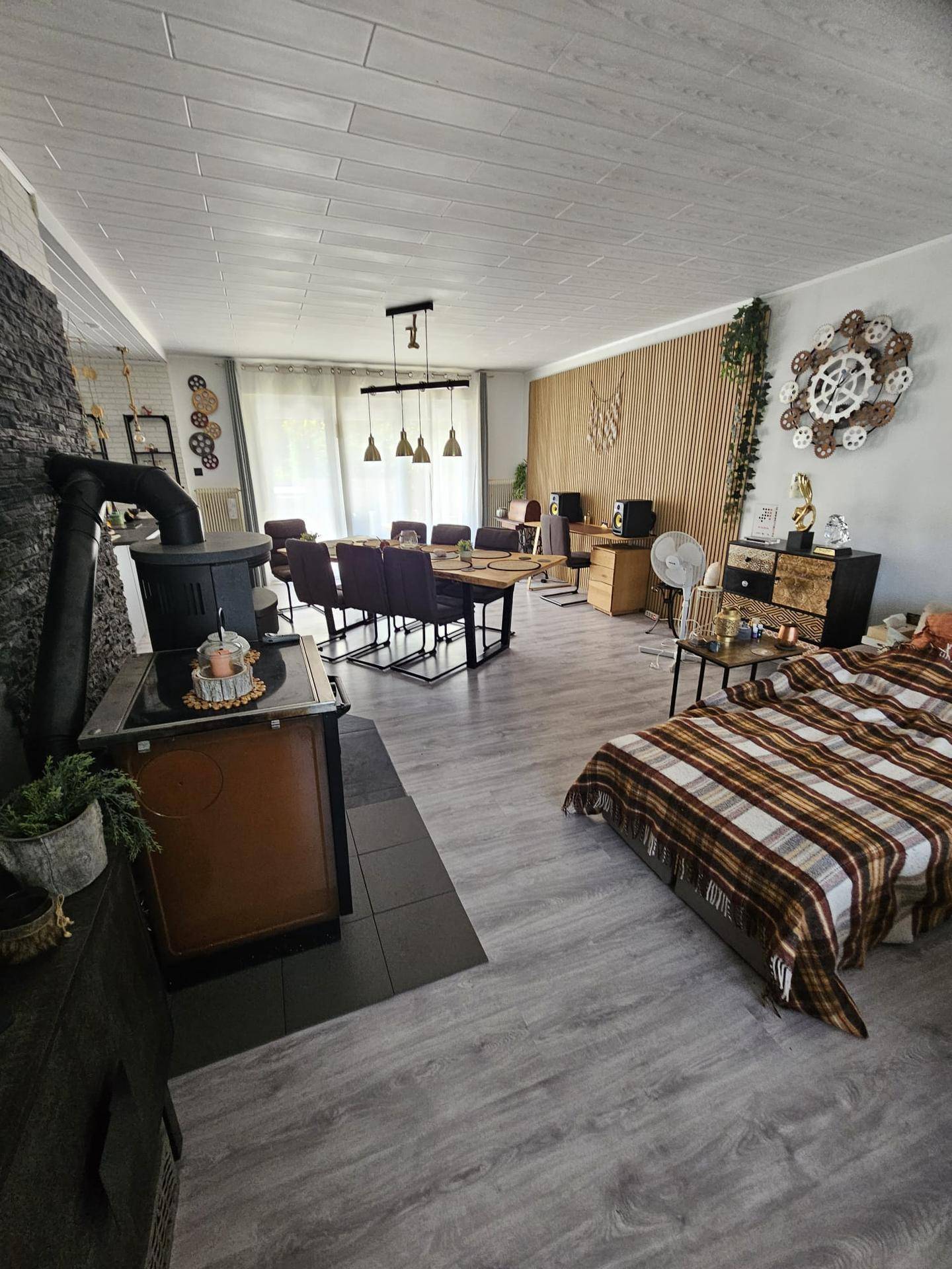Heller Wohn-Essbereich mit Holzboden, Kaminofen und moderner Dekoration.