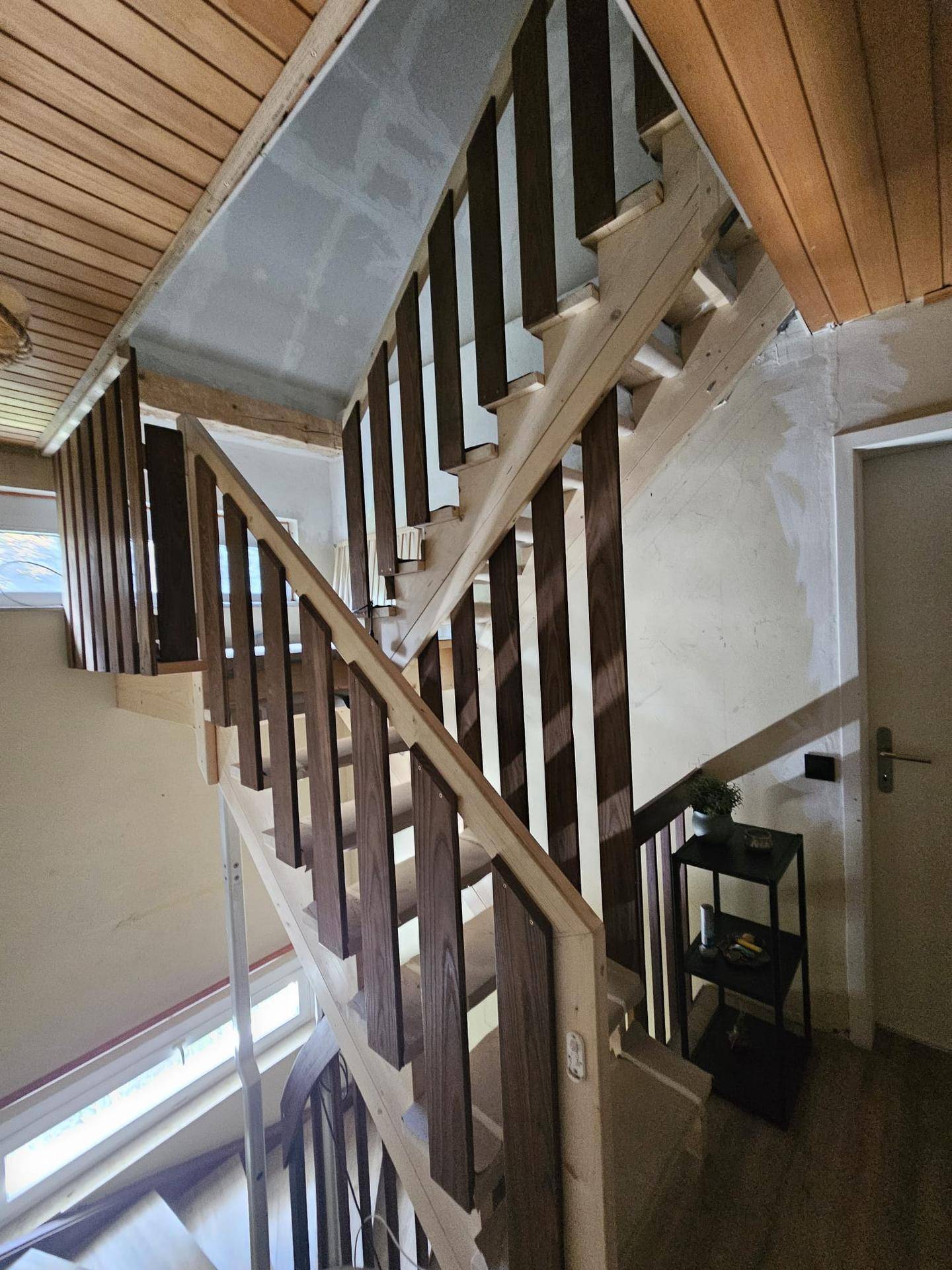 Holztreppe mit Geländer, die die verschiedenen Etagen des Hauses verbindet.
