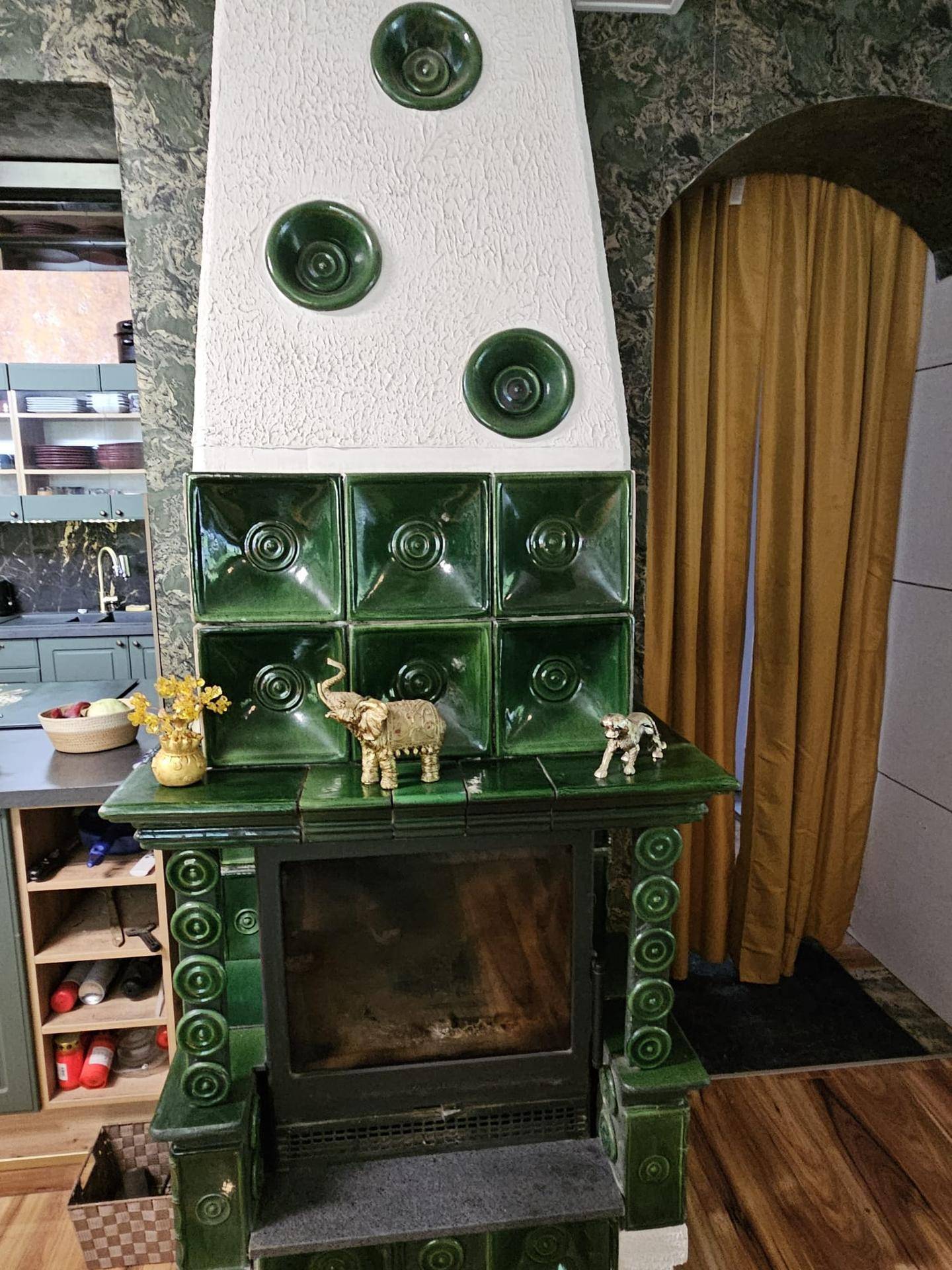 Traditioneller grüner Kachelofen als zentrales Heizelement im Wohnbereich.
