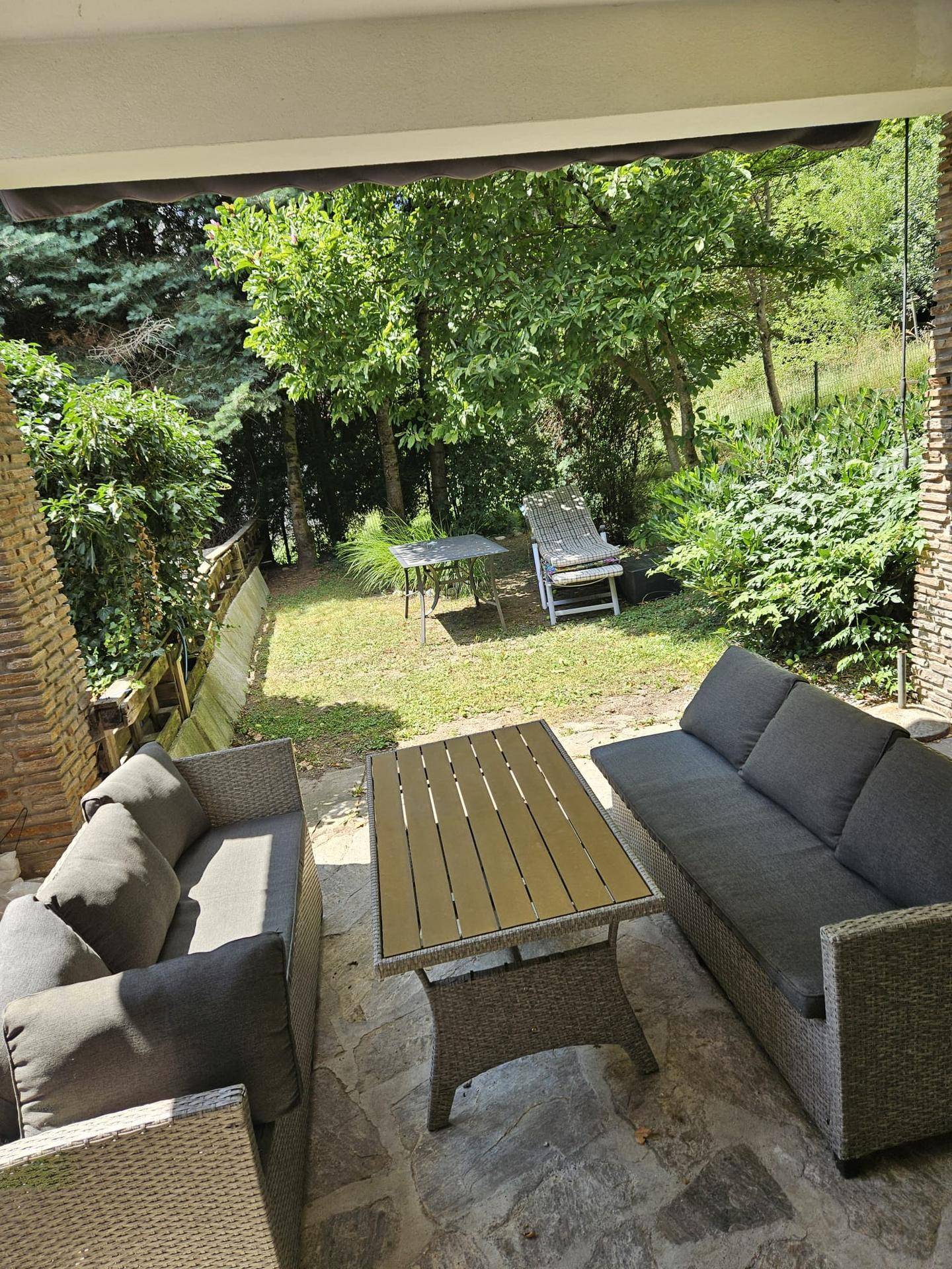 Überdachte Terrasse mit bequemen Loungemöbeln und Blick ins Grüne, ideal zum Entspannen.