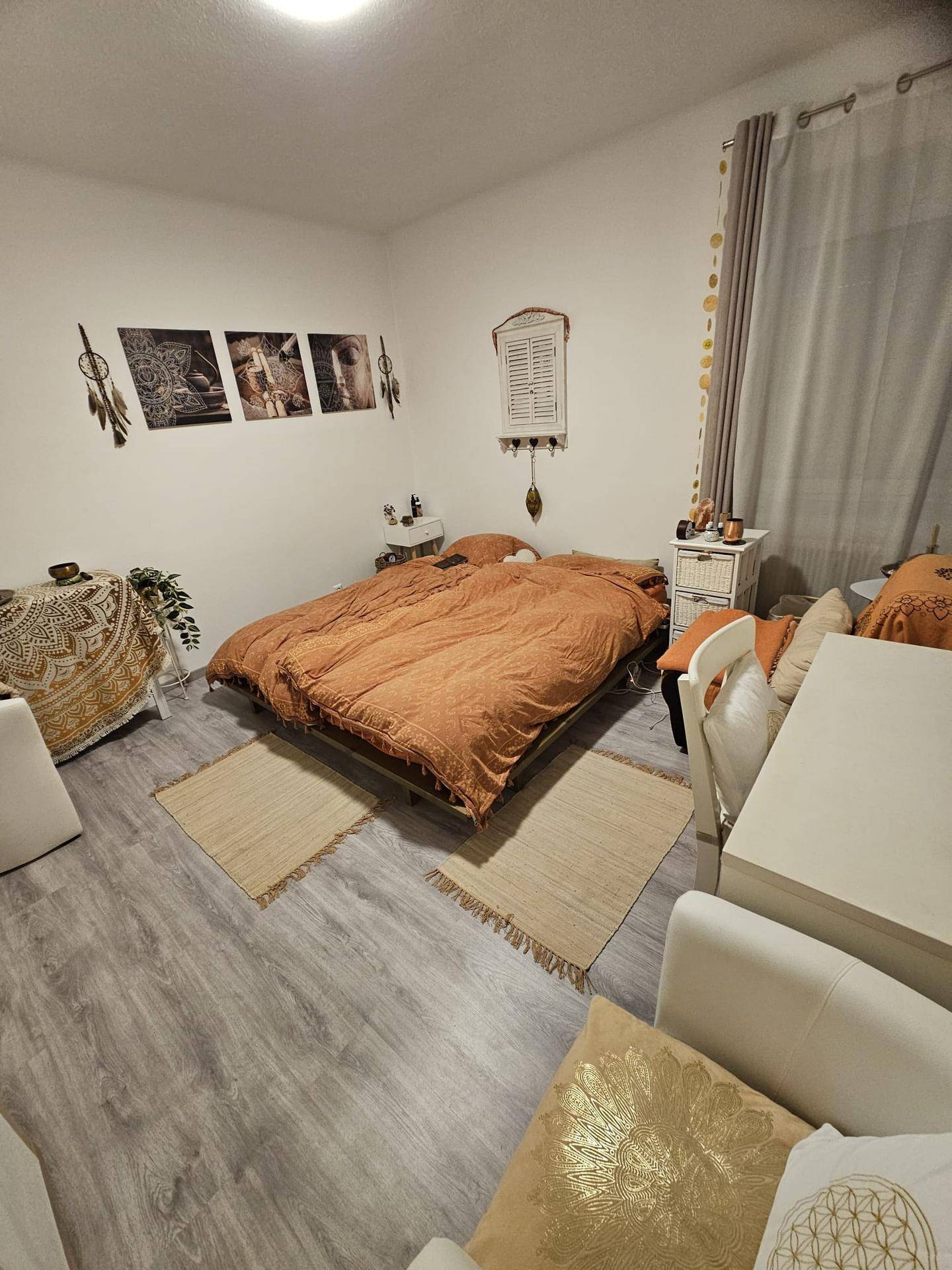 Schlafzimmer mit Doppelbett, hellem Laminatboden und dekorativen Elementen an der Wand.