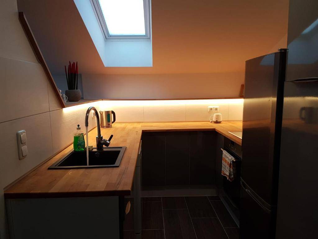 Kleine Küche im Dachgeschoss mit Holz-Arbeitsplatten, Spüle und Dachfenster.