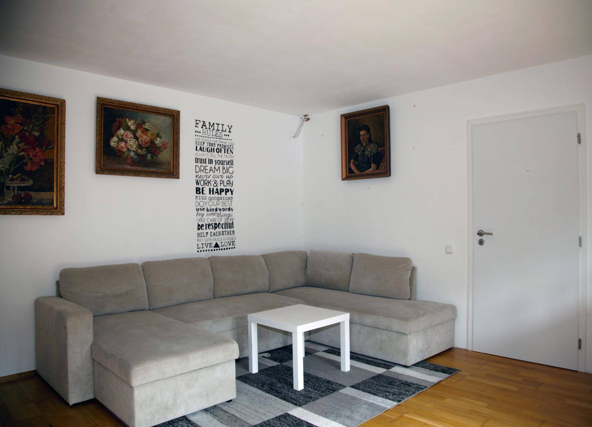 Gemütliches Wohnzimmer mit großem Ecksofa, Couchtisch und Bildern an der Wand.