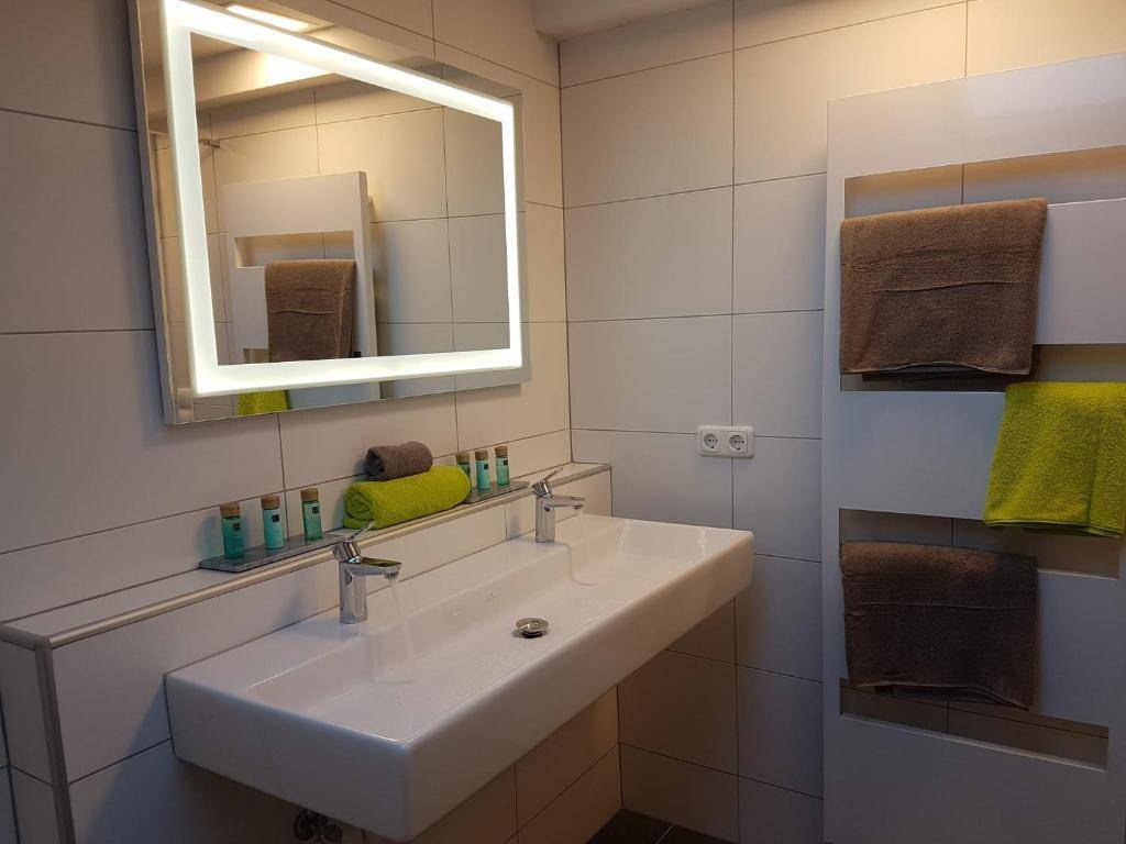 Modernes Badezimmer mit Doppelwaschbecken, beleuchtetem Spiegel und Handtuchheizkörper.