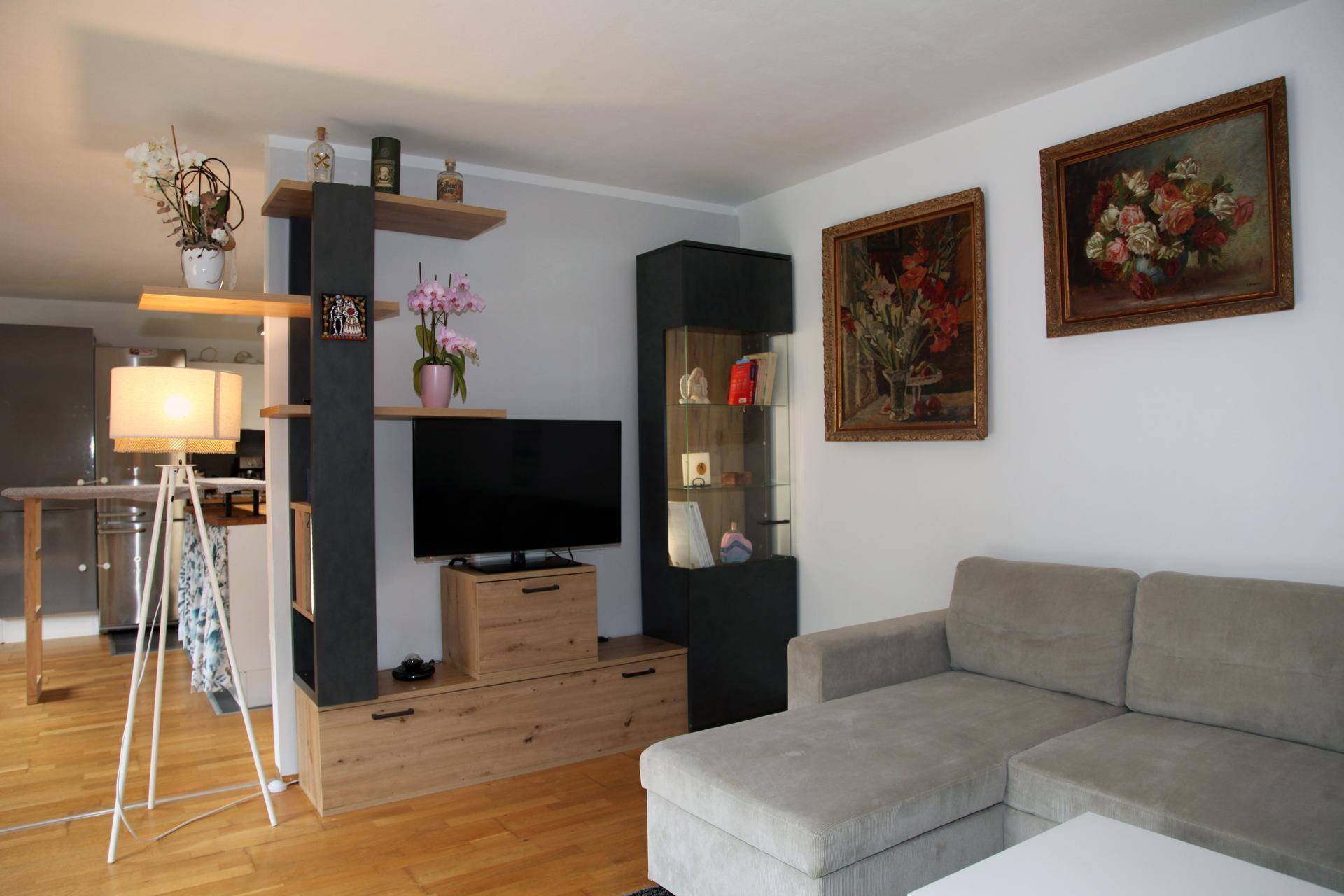 Heller Wohnbereich mit Sofa, TV-Möbel und offener Verbindung zur Küche.