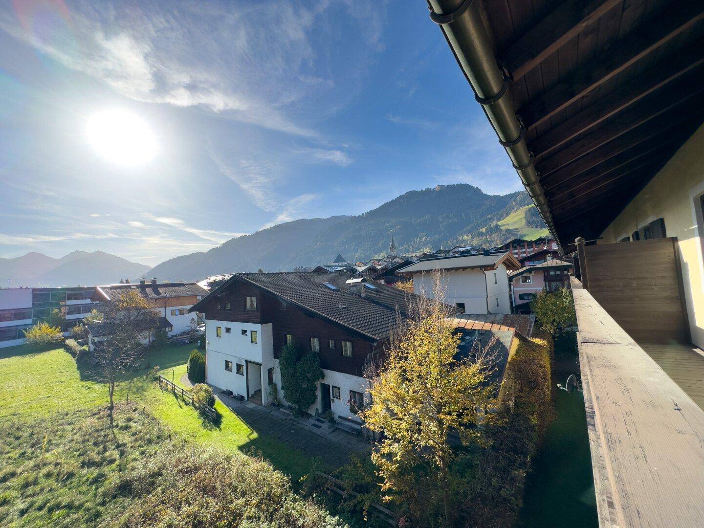 Sonniger Balkon mit Holzboden und Geländer, bietet einen weiten Blick auf die umliegende Berglandschaft.
