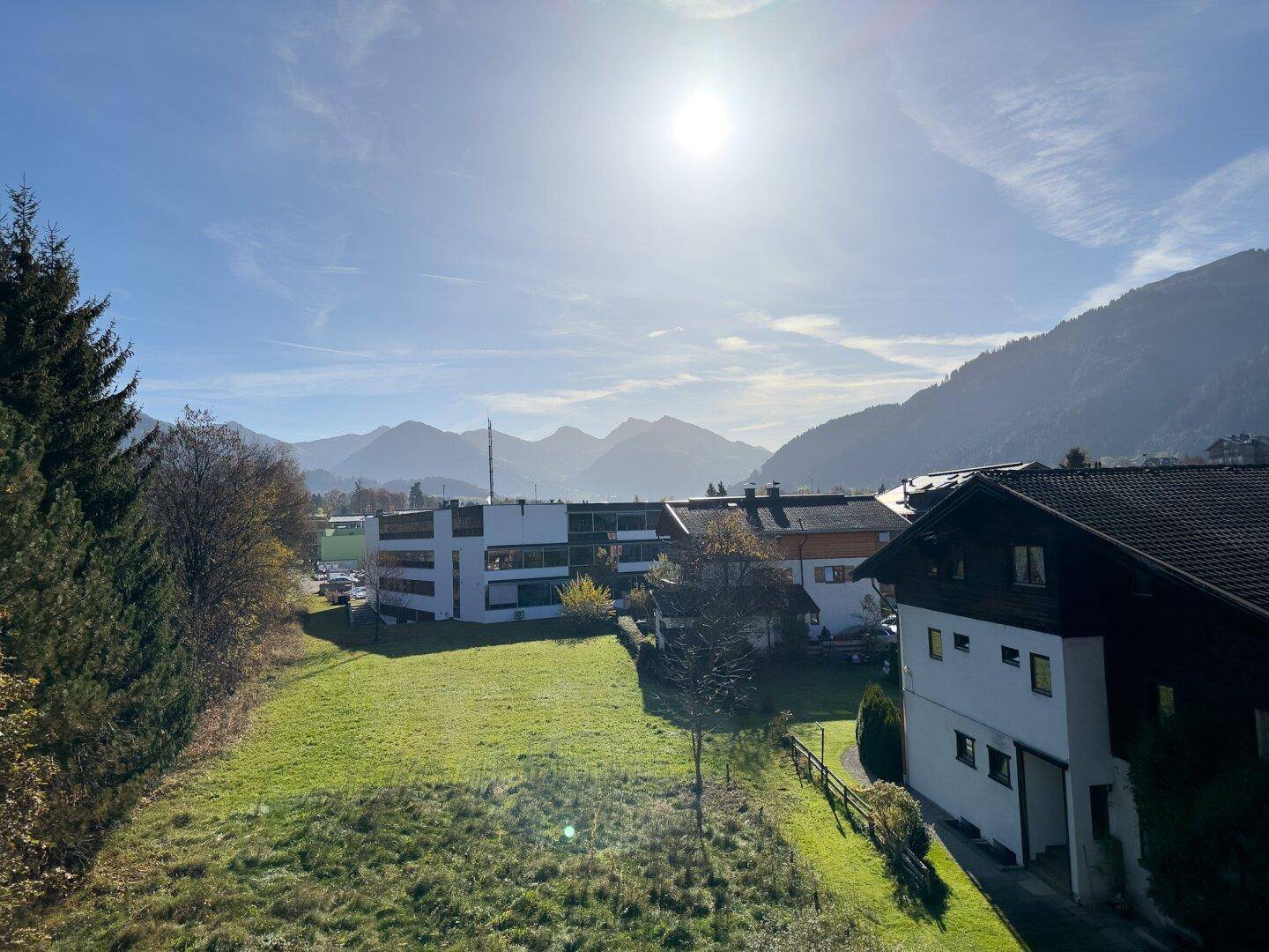 Sonniger Ausblick auf die umliegende Berglandschaft und grüne Wiesen.