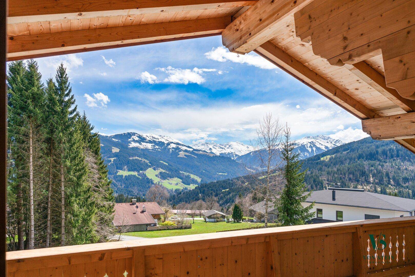 Atemberaubender Bergblick von einem traditionellen Holzbalkon mit weitem Horizont und blauem Himmel.