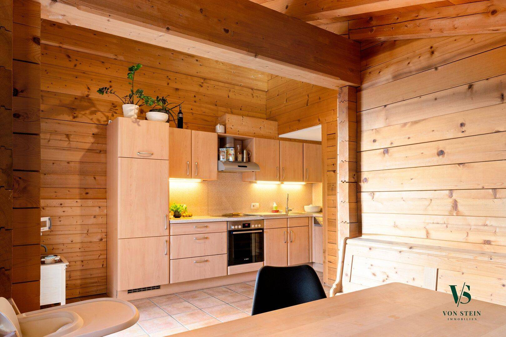 Funktionale Küche mit hellen Holzfronten, integrierten Geräten und Essbereich im alpinen Stil.