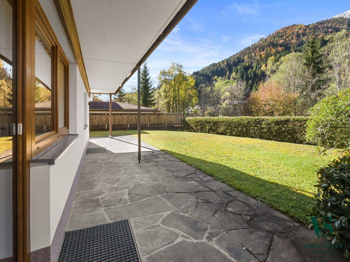 Geräumige Steinterrasse am Haus mit Überdachung und weitem Blick auf die umliegende Natur.