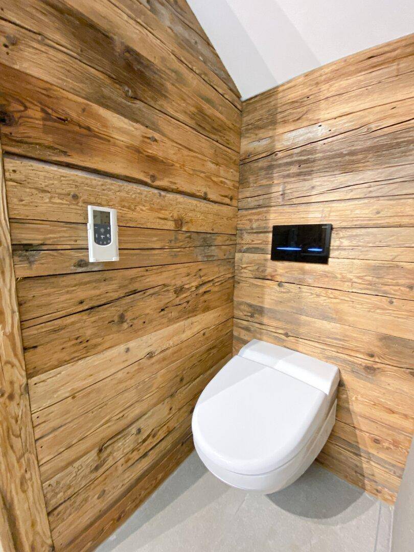 Separate Toilette mit Holzverkleidung und wandmontiertem WC.