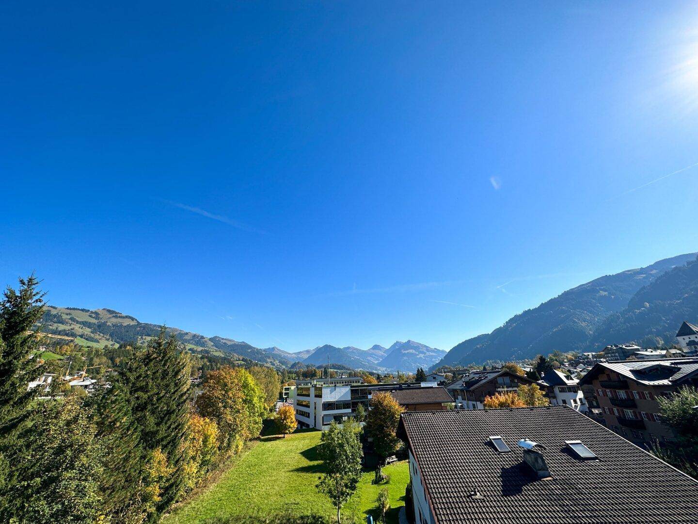 Weitläufiger Blick über die grüne Landschaft und die umliegenden Berge an einem sonnigen Tag.