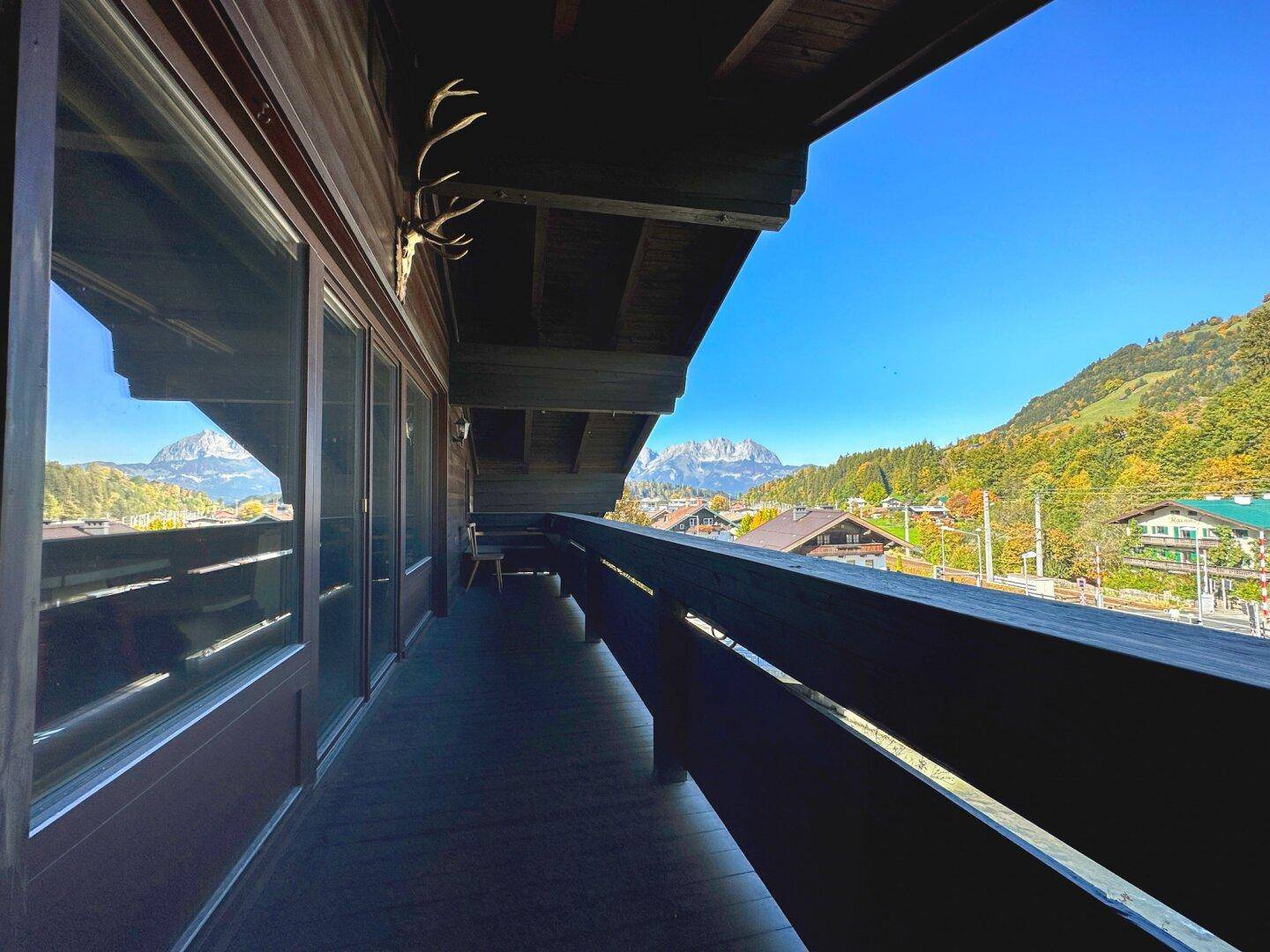 Geräumiger Holzbalkon mit Blick auf die Berge und die herbstliche Landschaft.