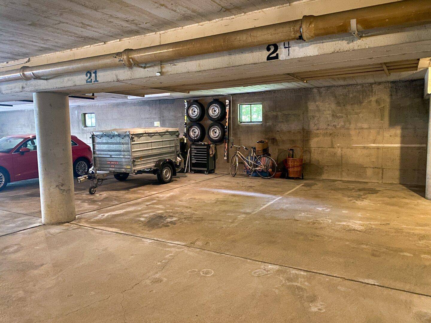 Tiefgarage mit Betonwänden, Stellplätzen und Abstellmöglichkeiten für Fahrräder.