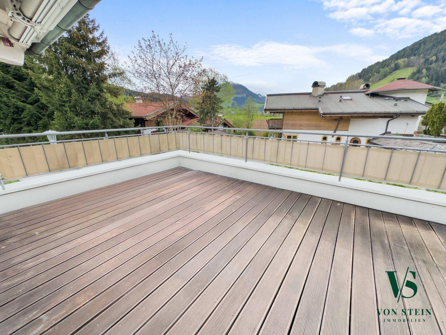 Große Holzterrasse mit Bergblick und umliegender Natur, ideal zum Entspannen.