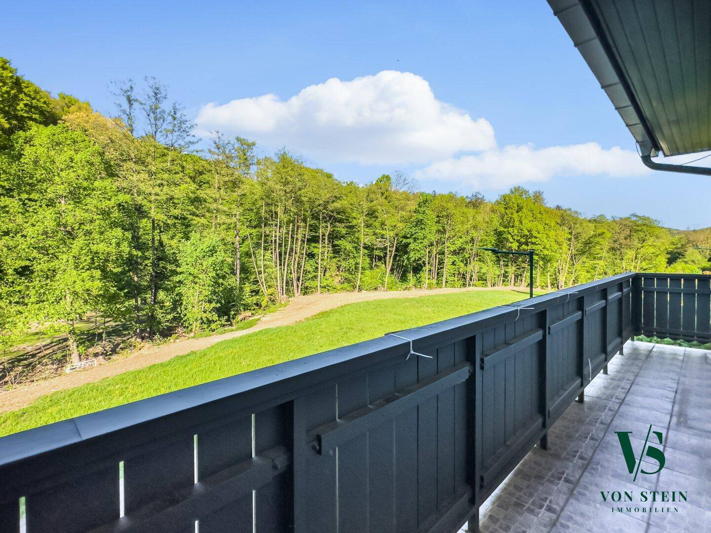 Geräumiger Balkon mit weitem Blick auf die grüne Landschaft und bewaldete Hügel.