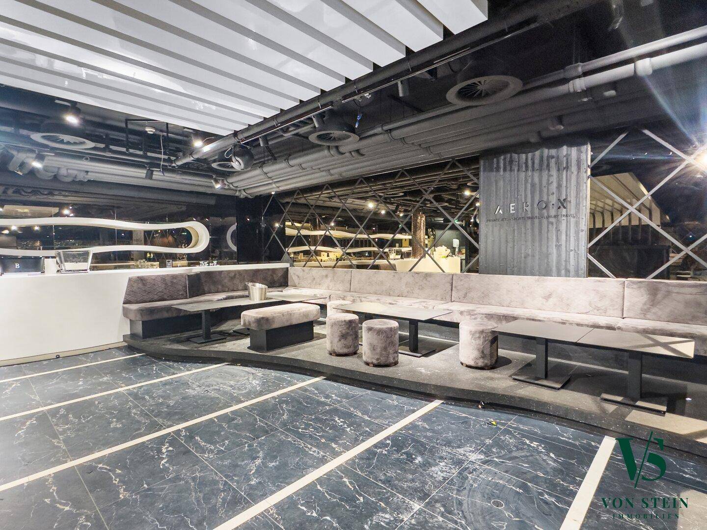 Moderner Lounge-Bereich mit bequemen Sitzgelegenheiten, dunklem Fliesenboden und stilvoller Beleuchtung.