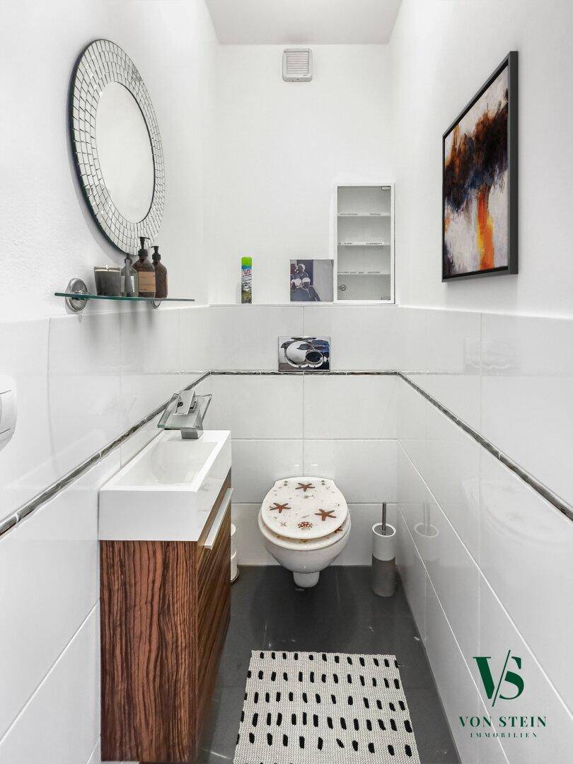 Modernes Gäste-WC mit Wand-WC, kleinem Waschbecken und dekorativem Spiegel.