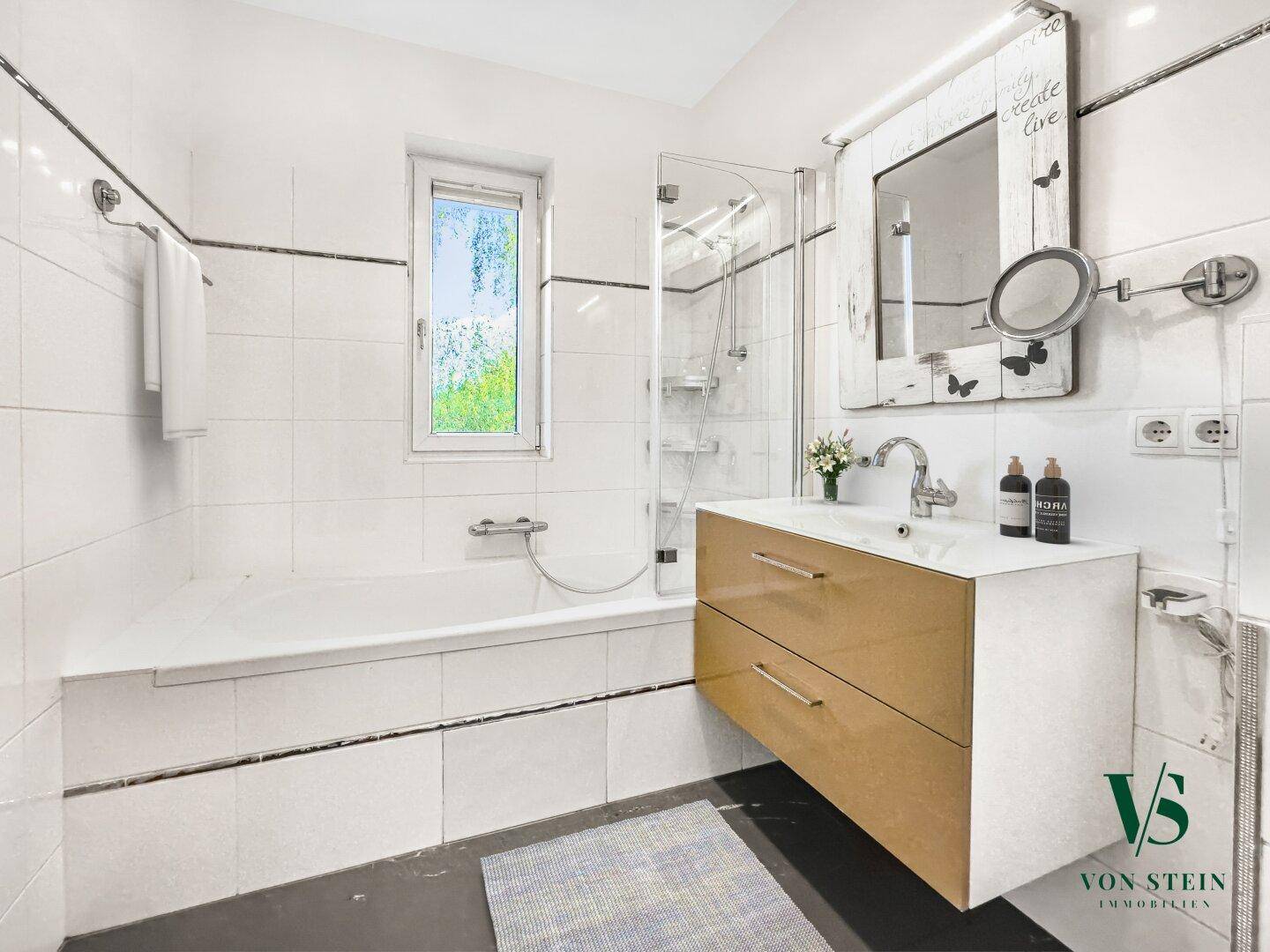 Badezimmer mit Badewanne, Dusche und Fenster, ausgestattet mit einem modernen Waschtisch.